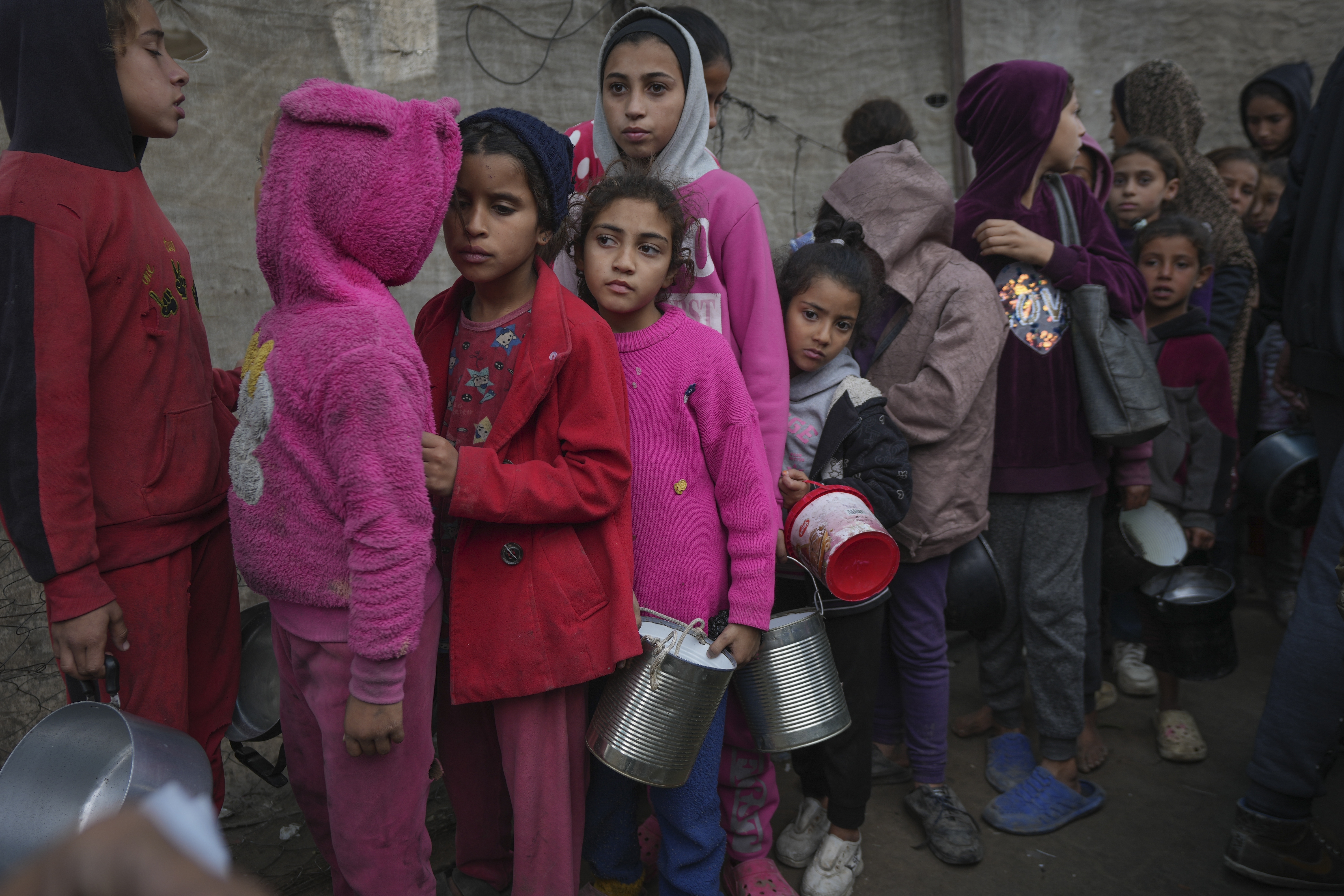 Palestinian children queue at a food distribution kitchen in Deir al-Balah, Gaza Strip