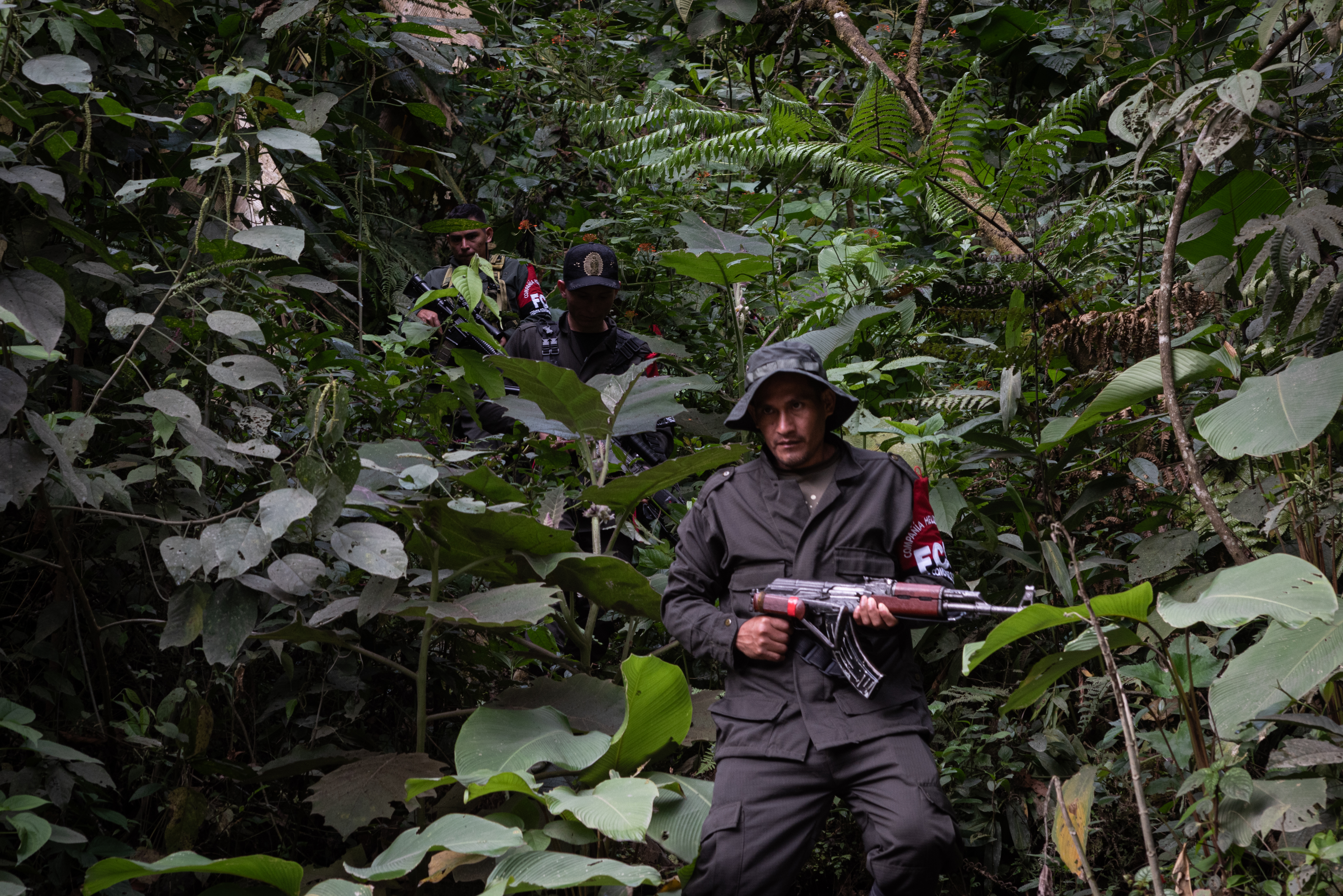A Comuneros del Sur fighter with a gun stands in the Colombian jungle.