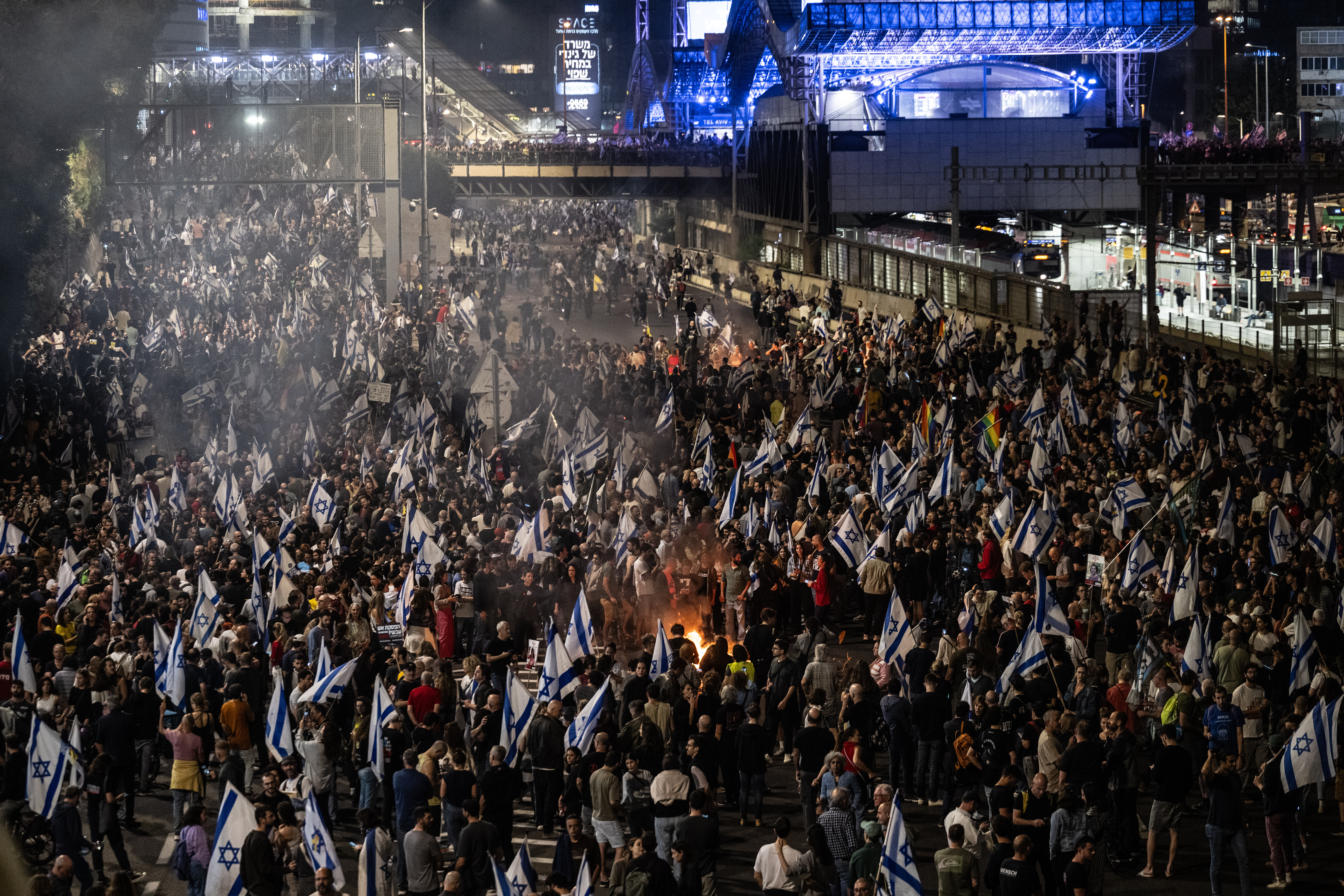 It's a bird's-eye view of a large crowd of protesters filling the street, and many Israeli flags.