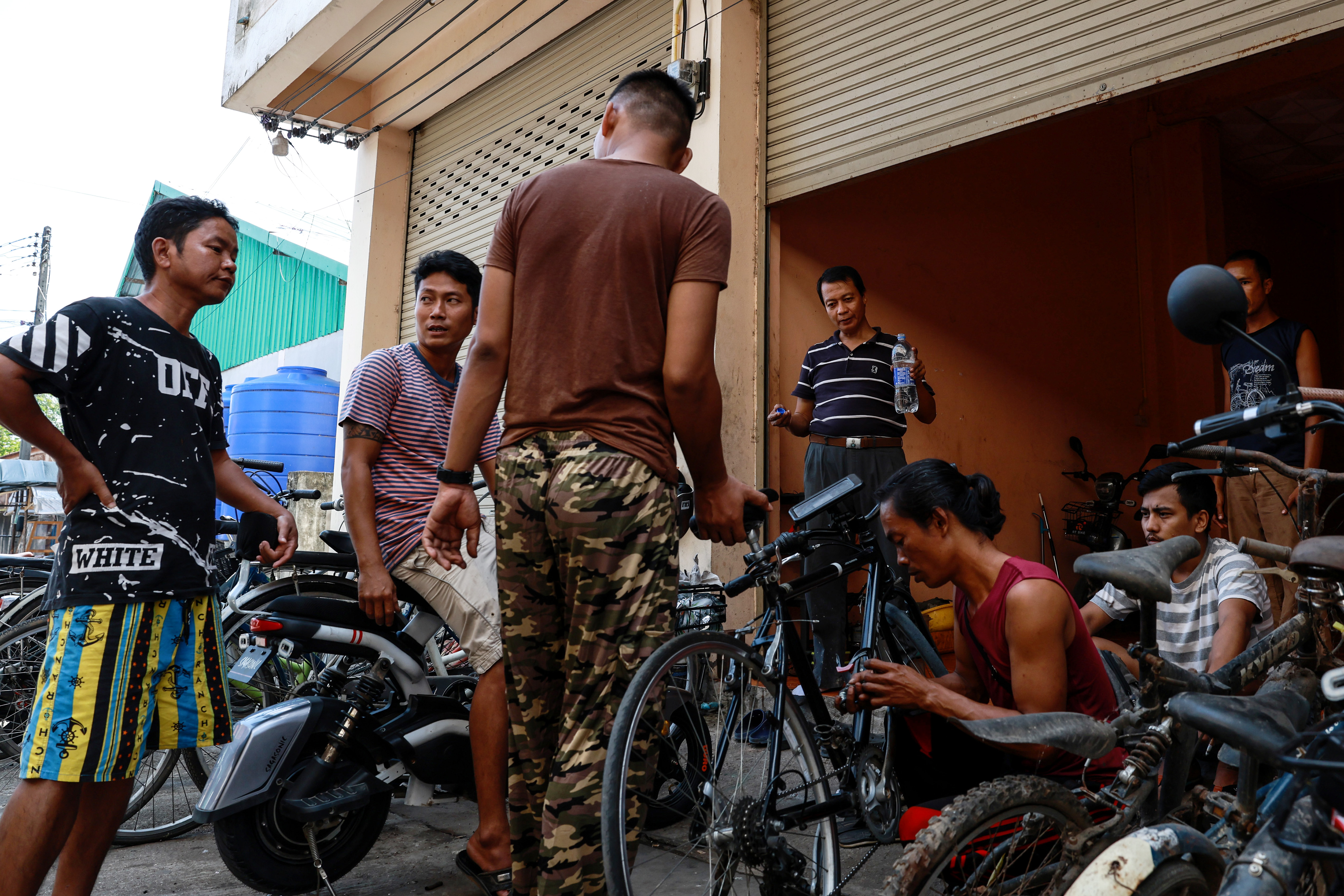 A repair instructor, former Myanmar navy personnel, center left, and regime defectors stand among bicycles during an e-bike and bicycle repair workshop near the Thailand-Myanmar border on November 1, 2024. [Valeria Mongelli/Al Jazeera]