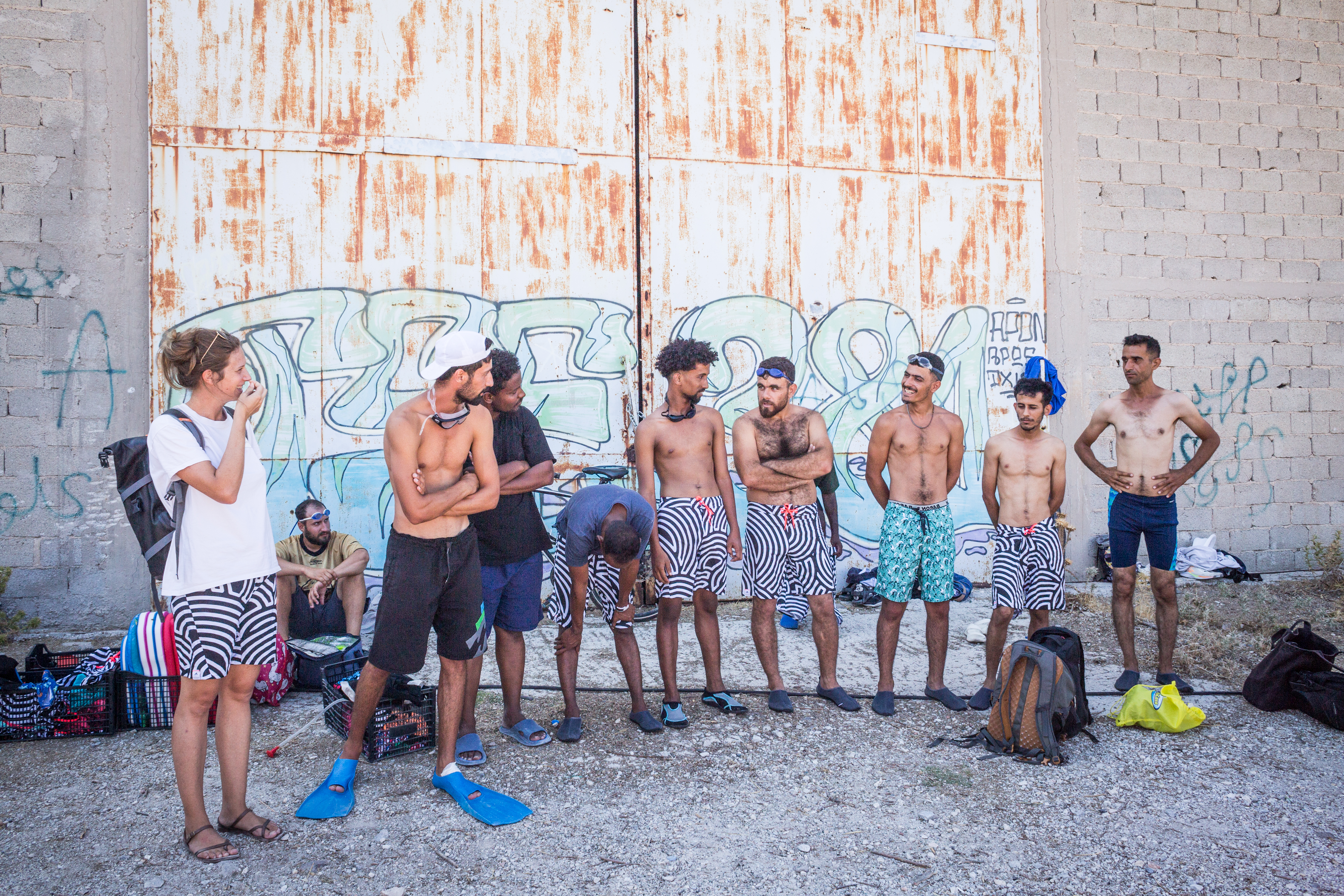 Emilie Bottini (left) works with the organisation “Terra Psy”, which provides psychological support to refugees in the community centre in Paréa on the island of Lesvo. She speaks with YSR swimmers before they enter the water. [Giacomo Sini/Al Jazeera]