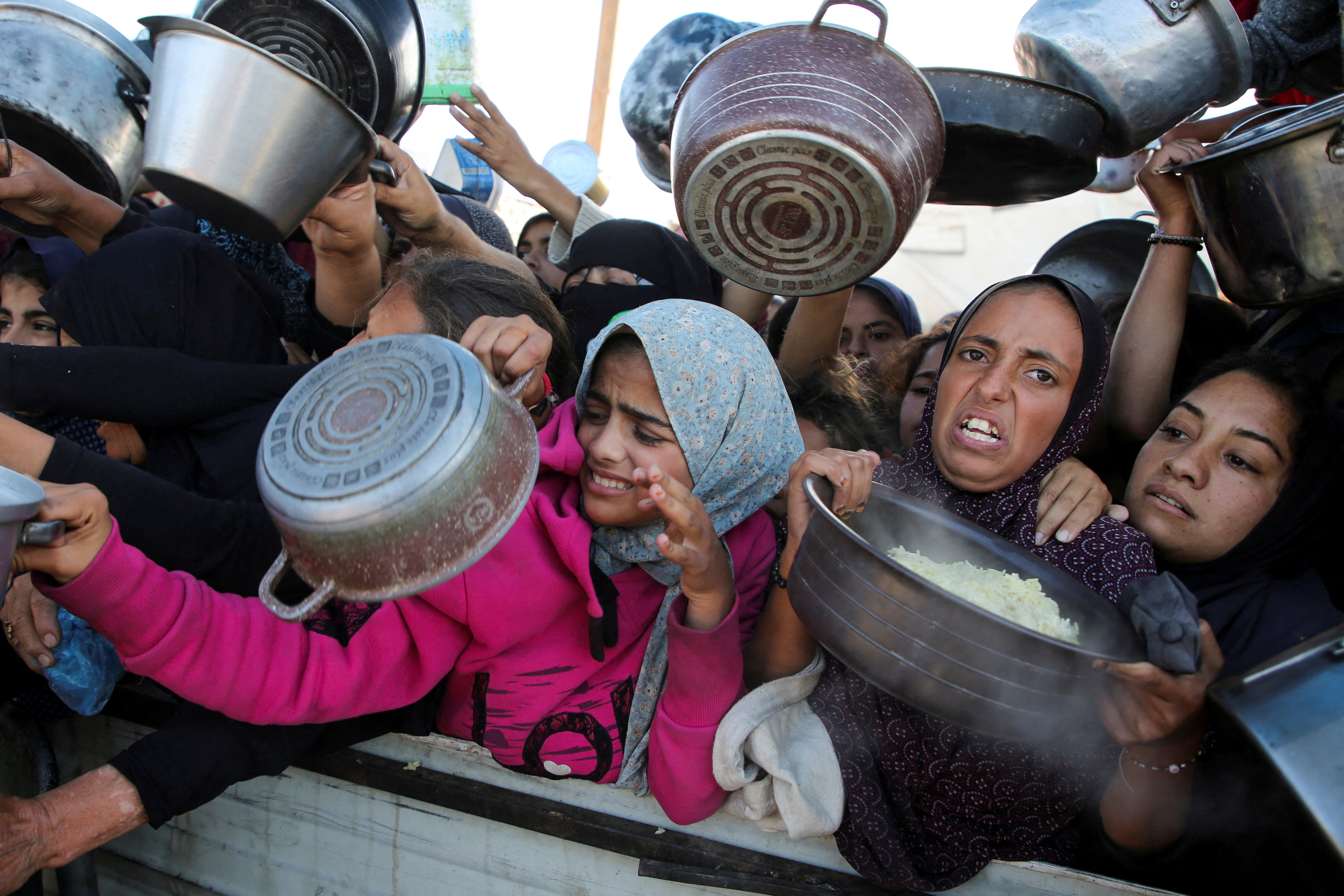 Palestinians gather to receive food cooked by a charity kitchen