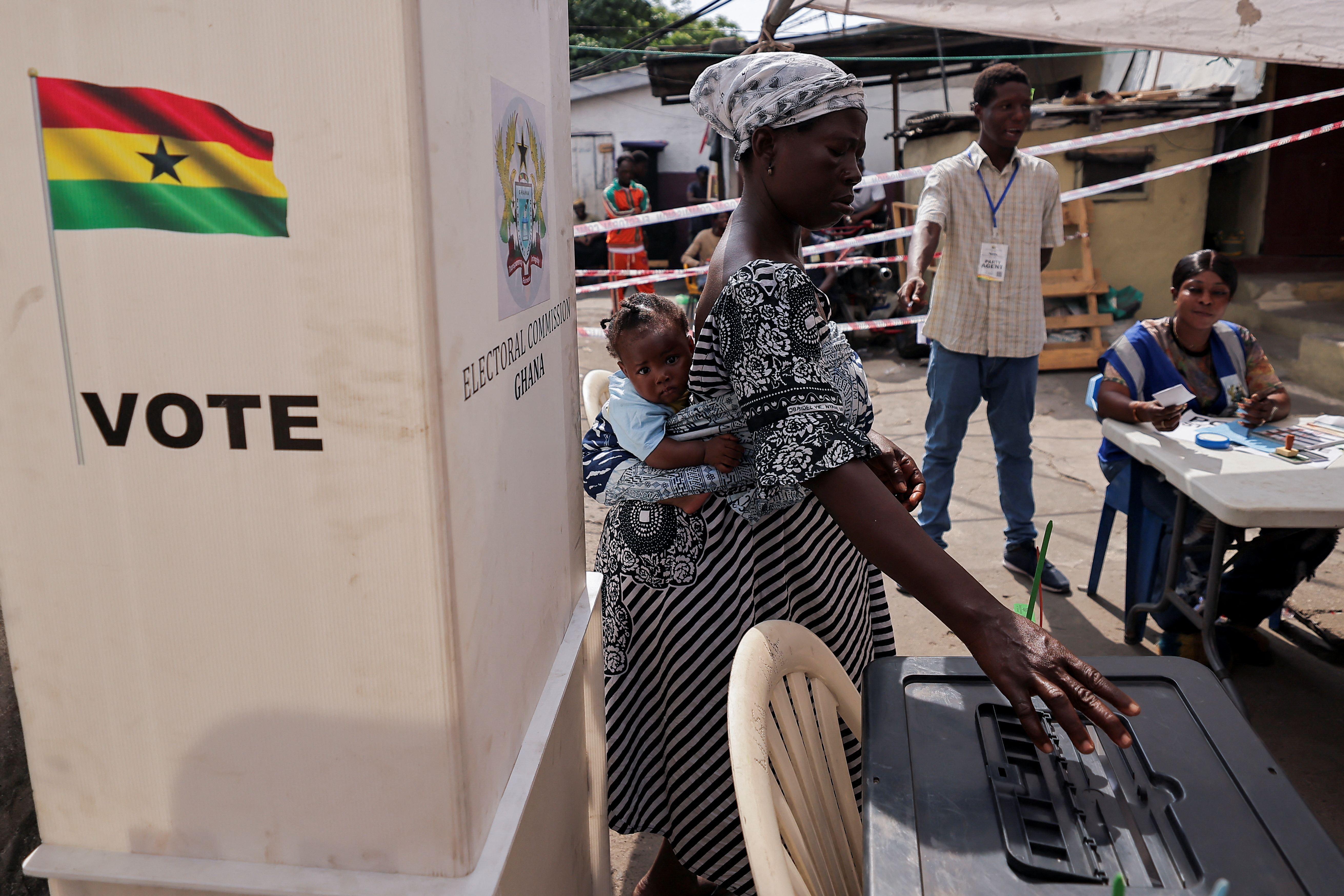 A woman carrying a child votes at a polling station in Ghana