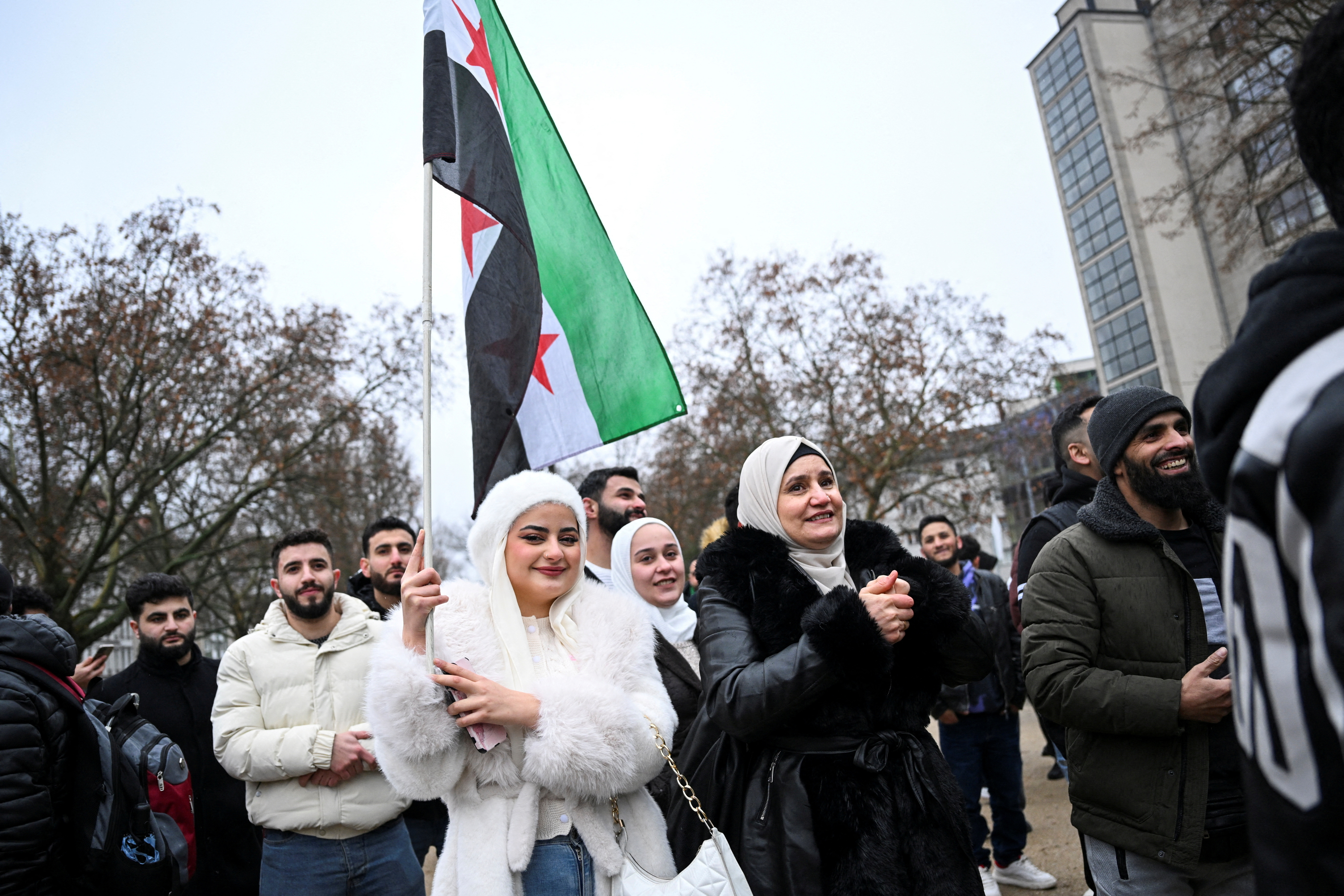 A woman carries a Syrian opposition flag, as people gather at Oranienplatz square, after Syrian rebels announced that they have ousted Syria's Bashar al-Assad, in Berlin, Germany December 8, 2024. REUTERS/Annegret Hilse REFILE - CORRECTING FROM "SYRIAN FLAG" TO "SYRIAN OPPOSITION FLAG".