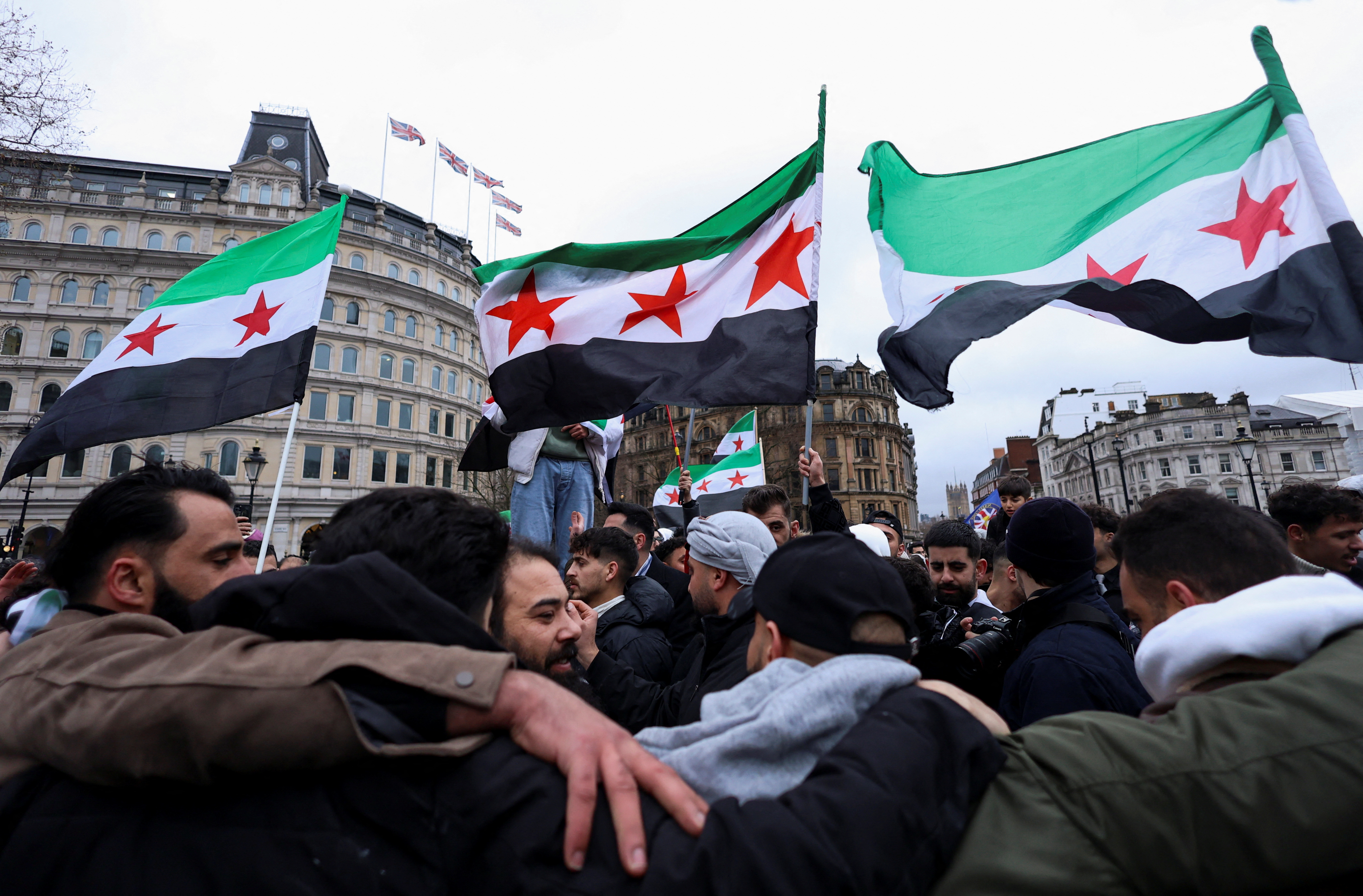 People wave Syrian opposition flags as they gather in Trafalgar Square