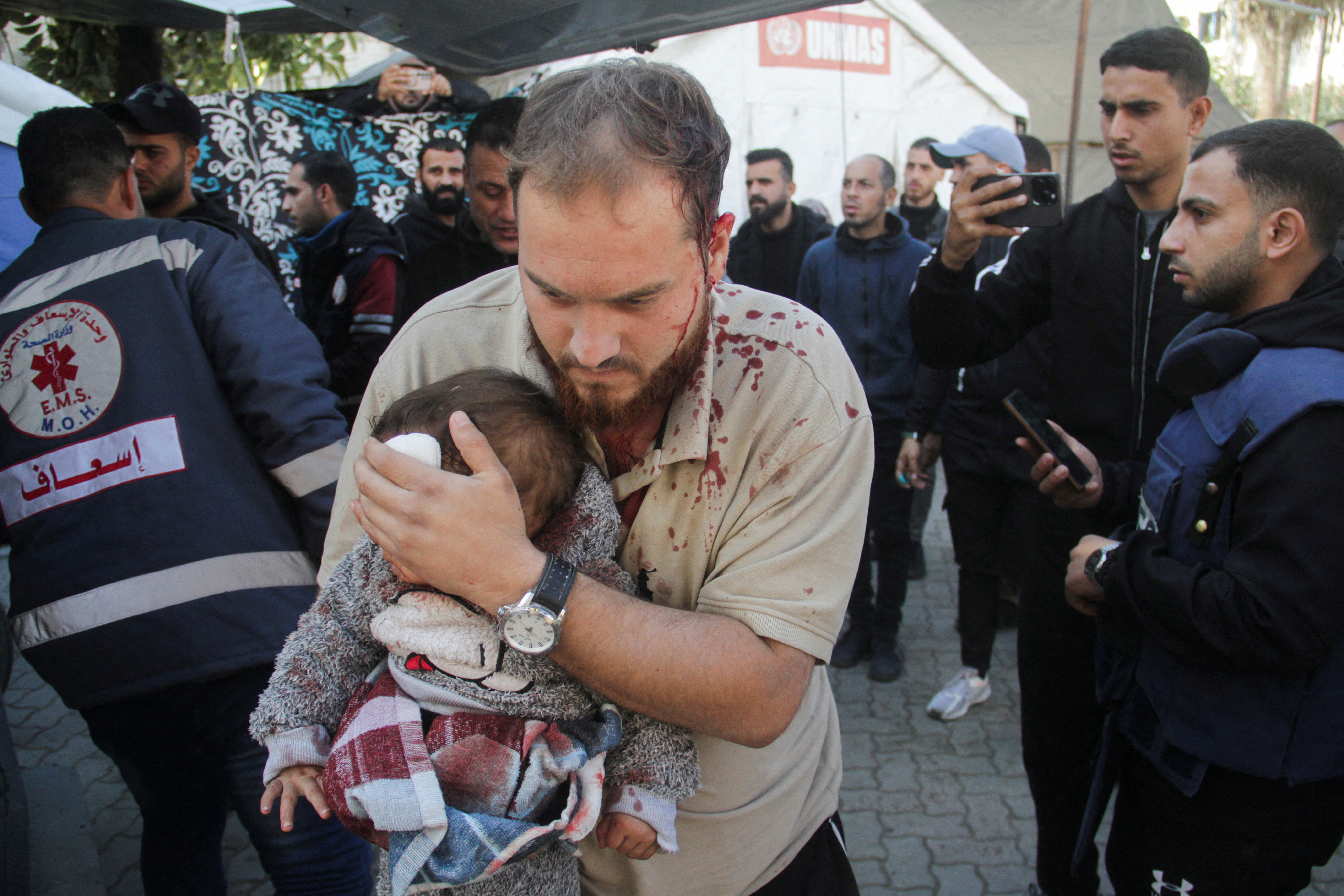 A Palestinian man carries a child casualty at a hospital, in the aftermath of an Israeli strike on a school sheltering displaced people, amid the Israel-Hamas conflict, in Gaza City December 14, 2024. REUTERS/Mahmoud Issa REFILE - CORRECTING "AT THE SITE OF AN ISRAELI STRIKE" TO "AT A HOSPITAL, IN THE AFTERMATH OF AN ISRAELI STRIKE".
