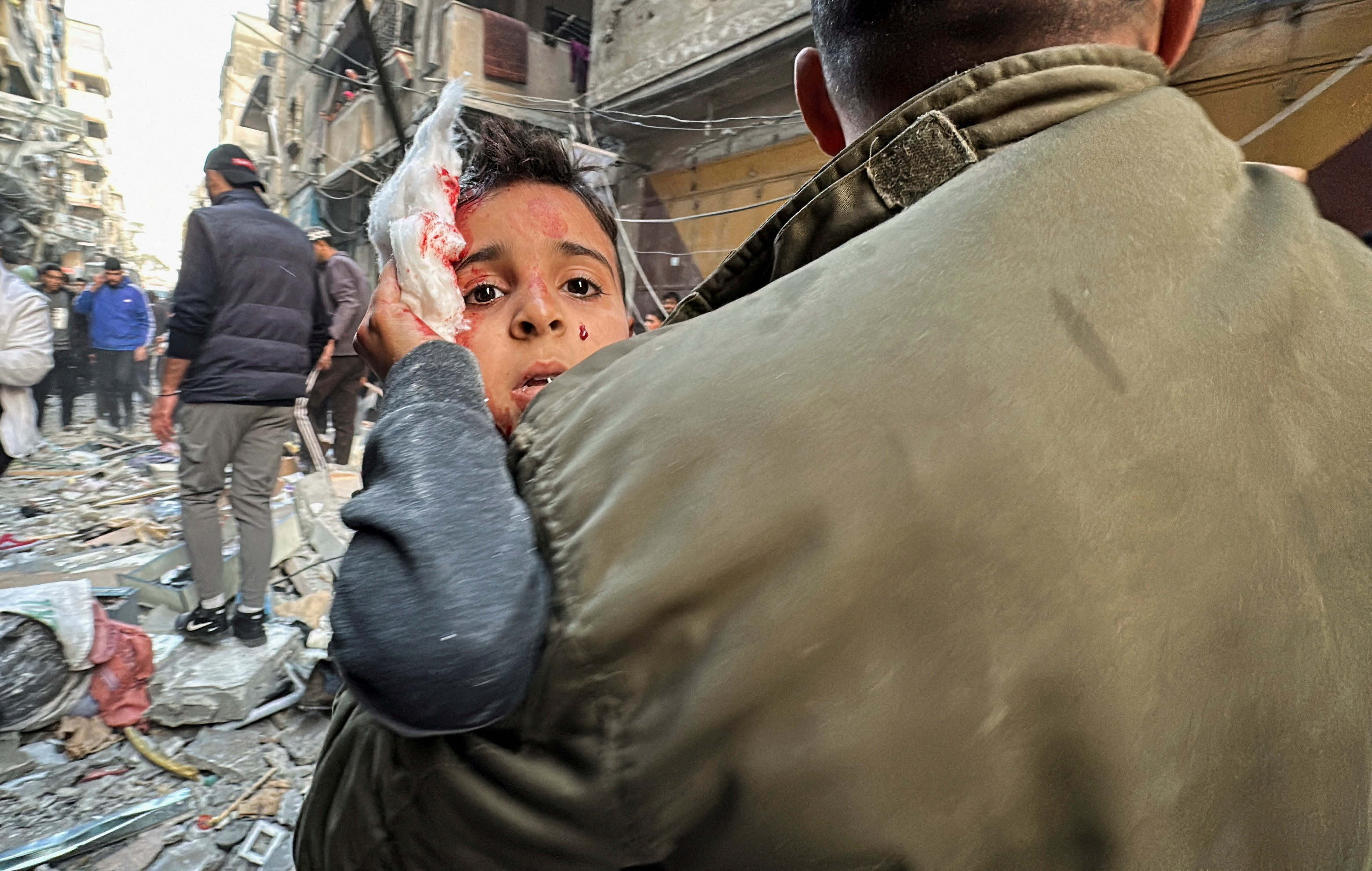 Palestinian carries a wounded child at the site of an Israeli strike on an apartment, amid the ongoing conflict between Israel and Hamas, in Nuseirat, central Gaza Strip.