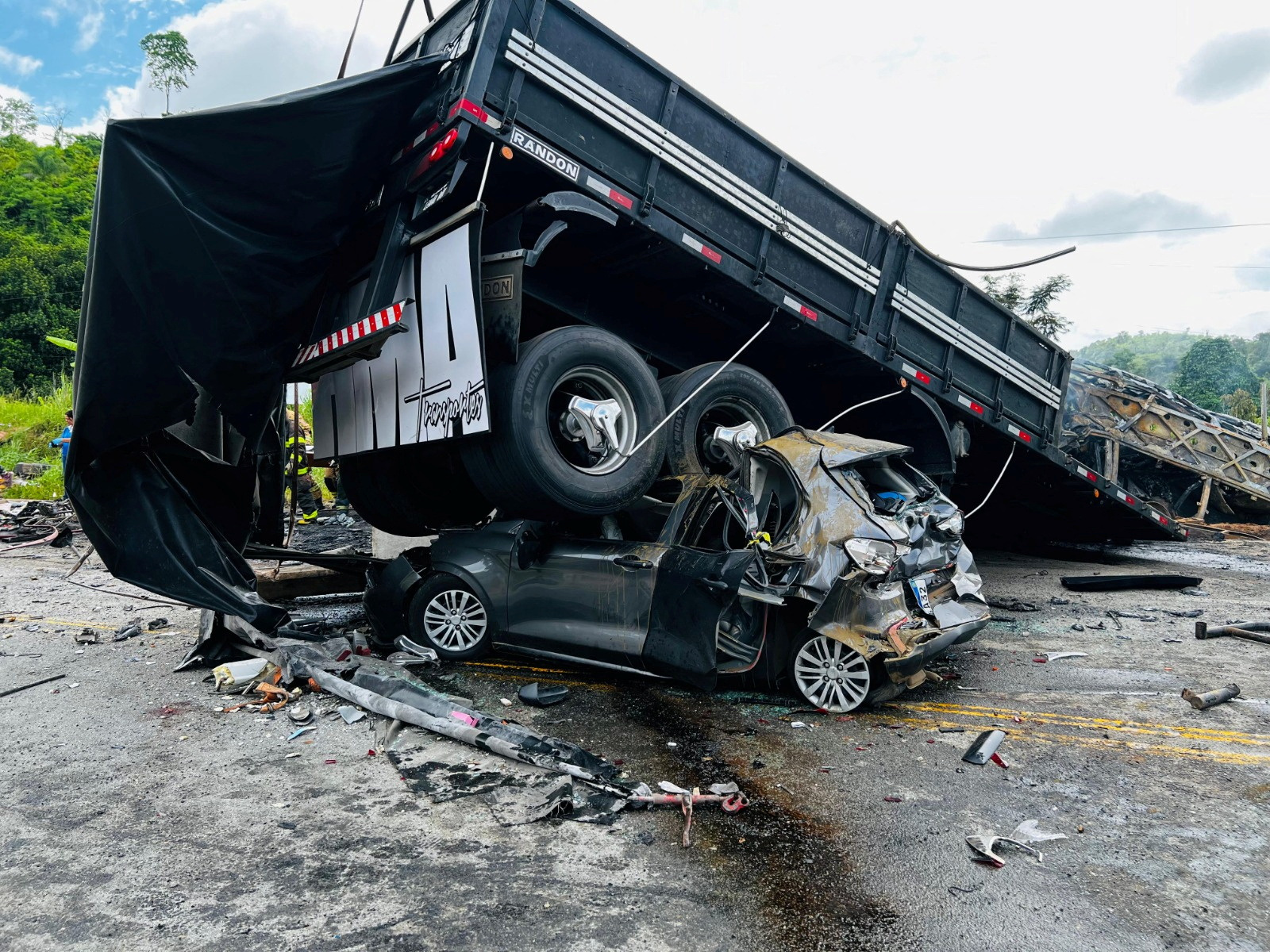 A damaged car is crushed under a vehicle following a traffic accident after a packed bus collided with a truck, at the Fernao Dias national highway, near Teofilo Otoni,