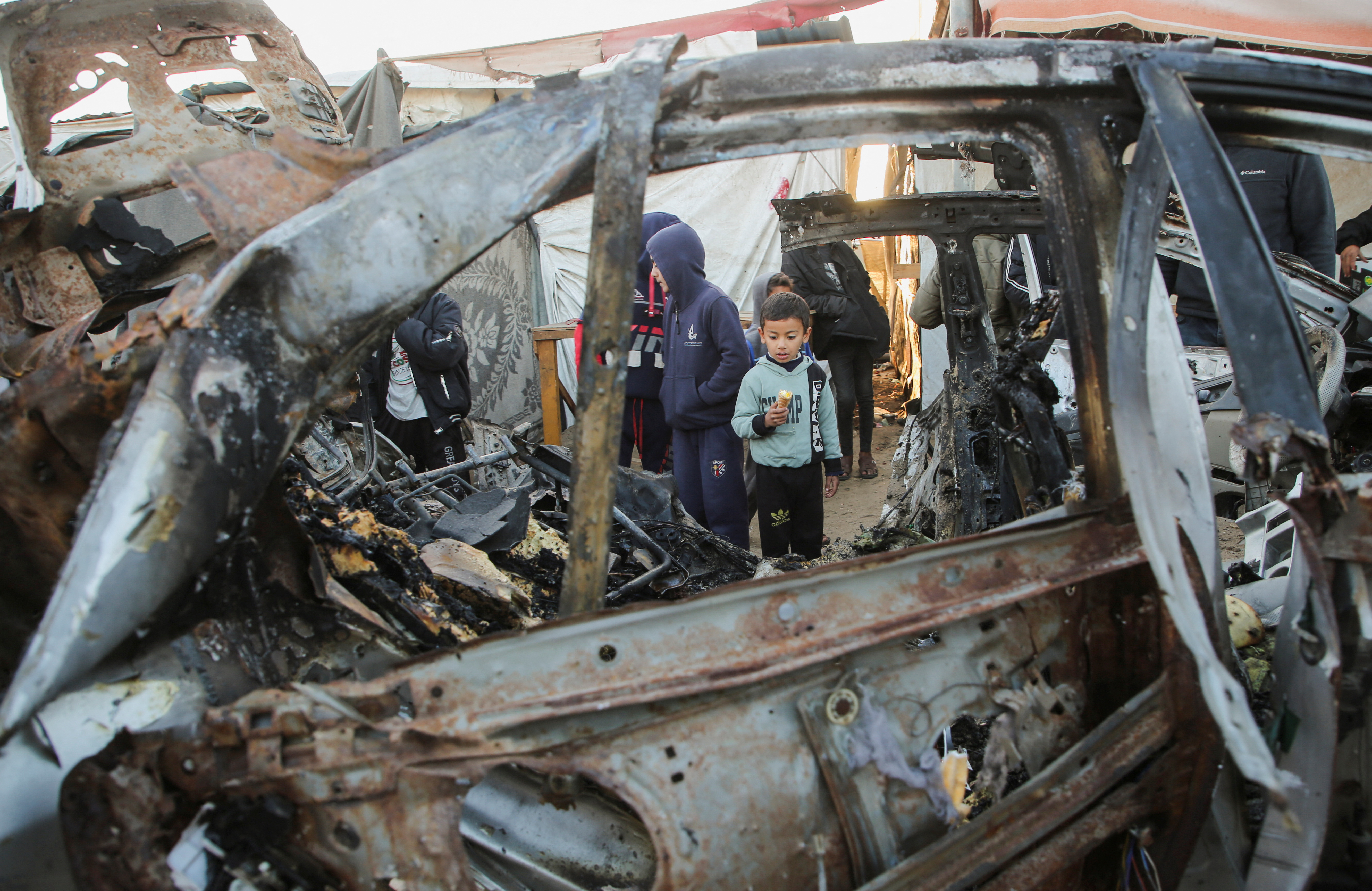Palestinian children inspect the remains of a car in the aftermath of an Israeli strike in Khan Younis in the southern Gaza Strip, December 23, 2024. [Hatem Khaled/Reuters]