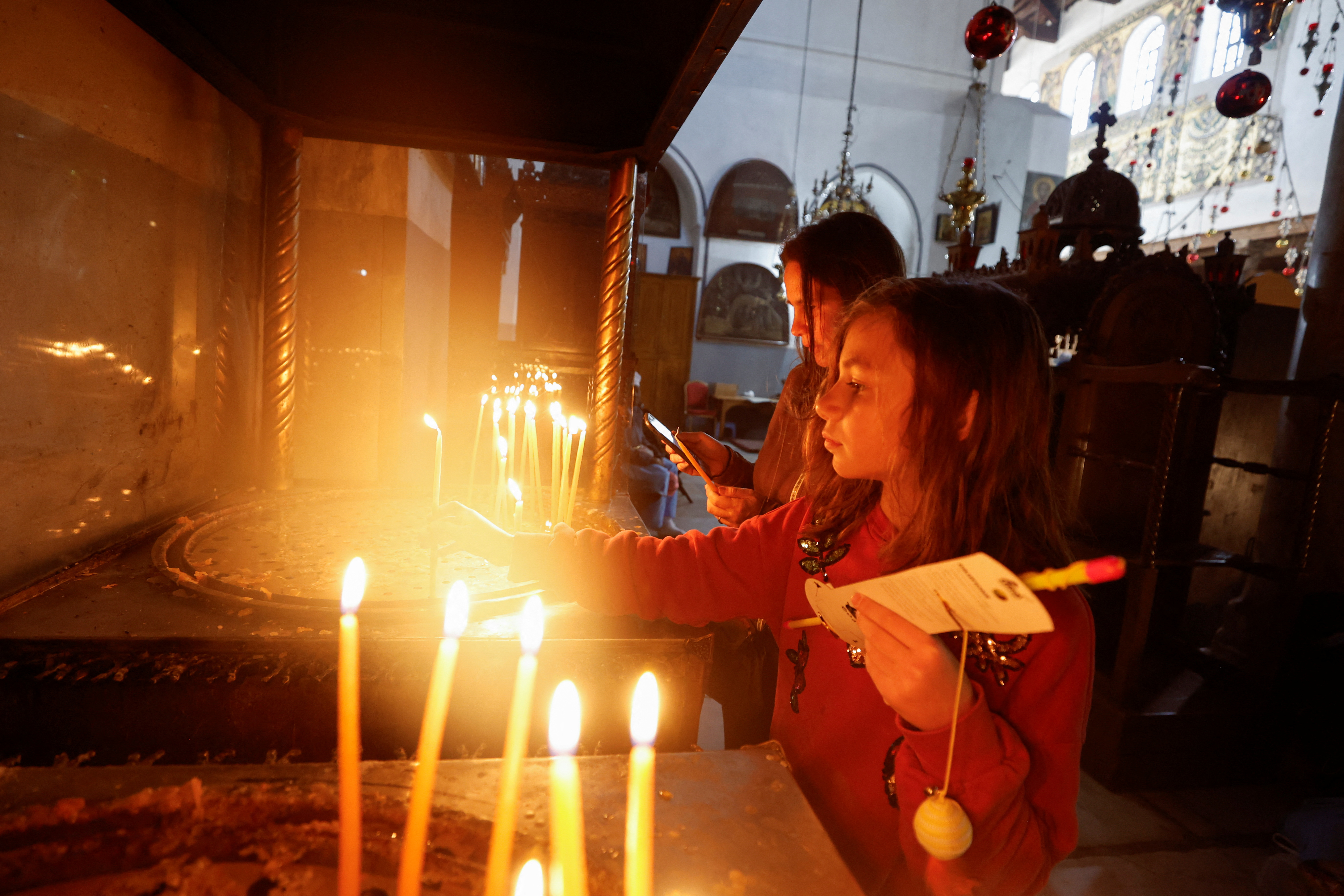People light candles at the Church of the Nativity ahead of the arrival of the Latin Patriarch of Jerusalem, Pierbattista Pizzaballa, in Bethlehem in the Israeli-occupied West Bank 