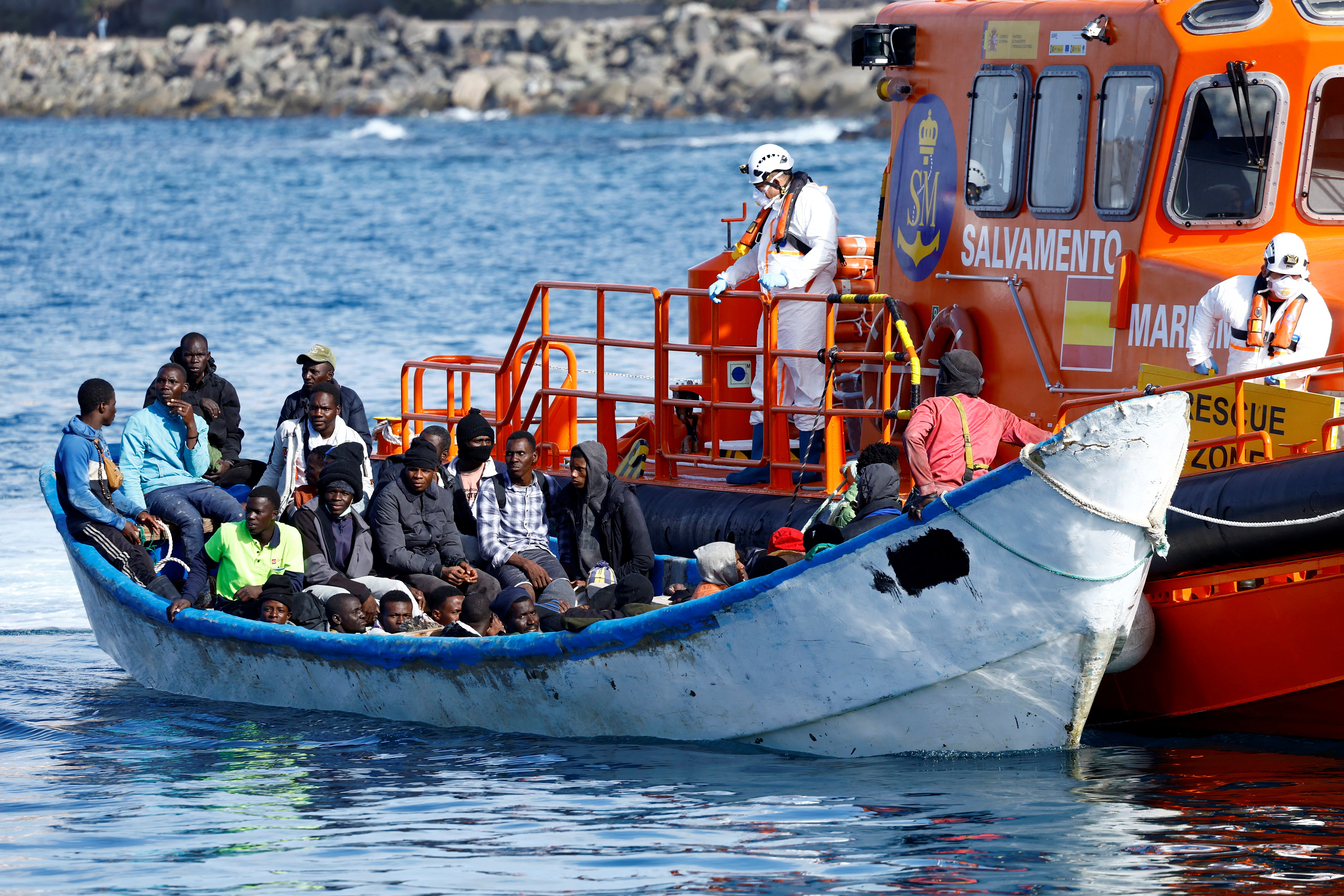 A Spanish Coast Guard vessel tows a fibreglass boat with migrants onboard