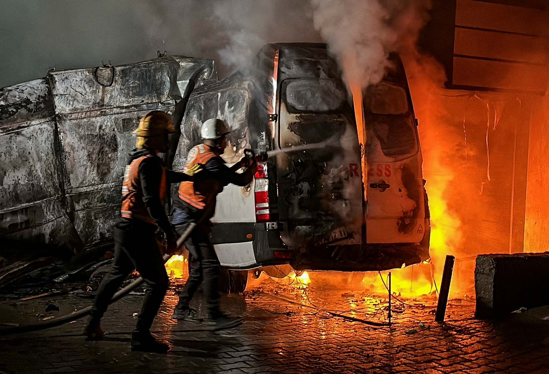 Civil Defense members put out a fire in a broadcast van following an Israeli strike that killed five journalists of Al-Quds Al-Youm television channel, according to medics with the Gaza health authorities, in the vicinity of Al-Awda hospital in Nuseirat in central Gaza December 26