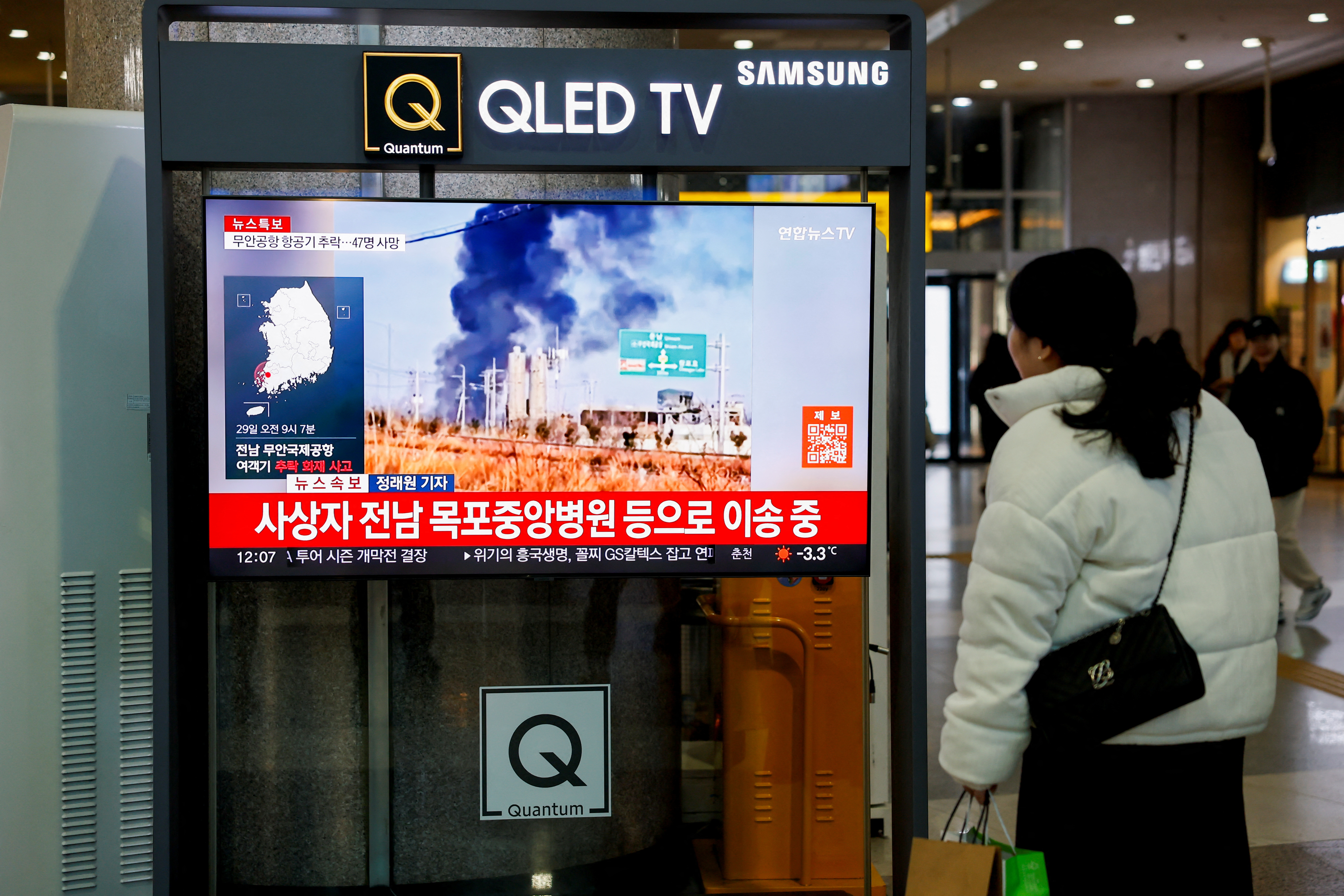 A woman watches a TV screen broadcasting footage of an aircraft crash at Muan International Airport, at a railway station in Seoul, South Korea, December 29, 2024. REUTERS/Kim Soo-hyeon