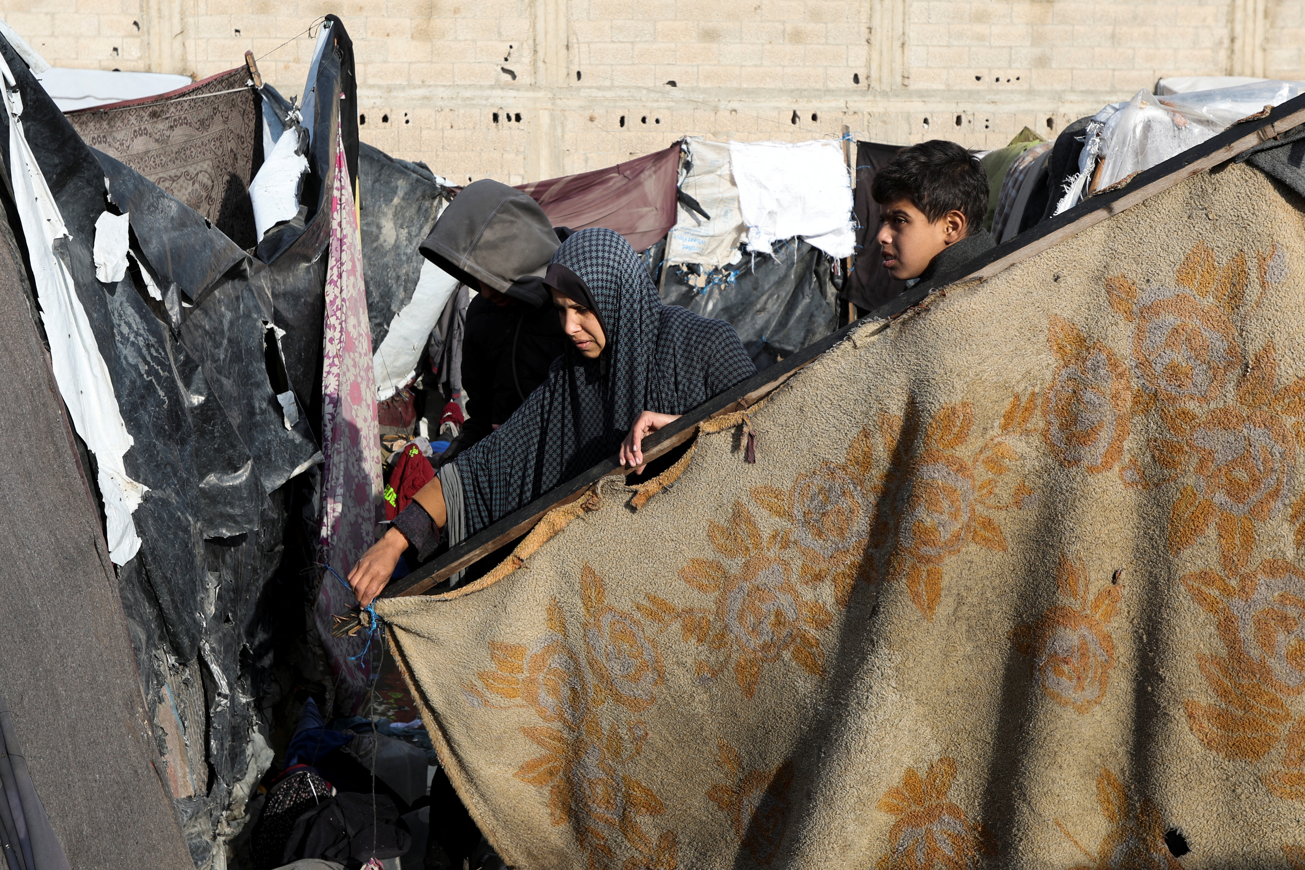 Displaced Palestinians walk at a tent camp where they shelter, following heavy rains, amid the Israel-Hamas conflict, in Deir Al-Balah, in the central Gaza Strip, December 30
