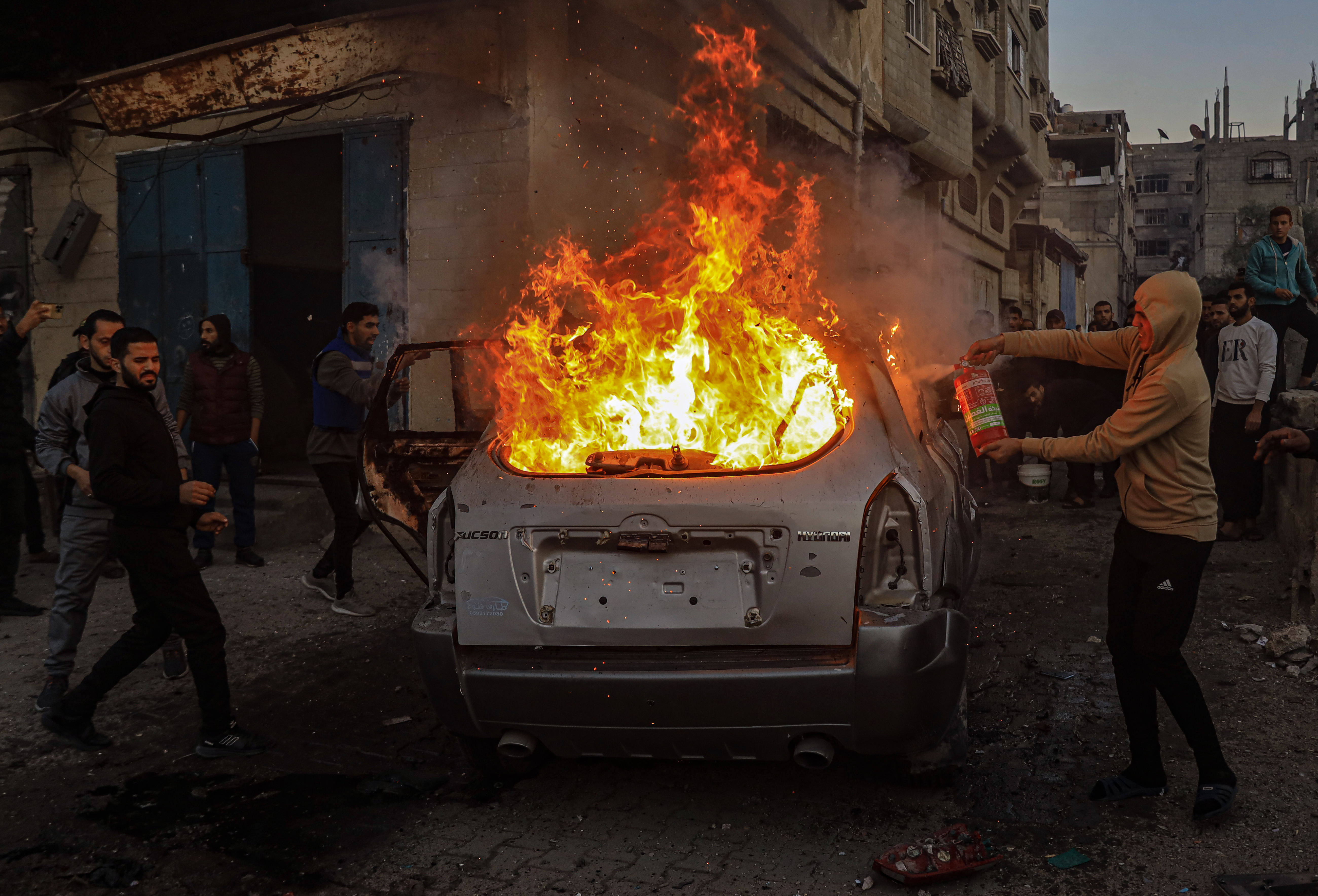 Palestinians try to extinguish a fire broke out on a vehicle as at least 15 Palestinians were killed and over 30 others injured on Thursday in an Israeli airstrike on Dar al-Arqam and Shaaban al-Rayes schools sheltering displaced people in Gaza City, Gaza on December 19