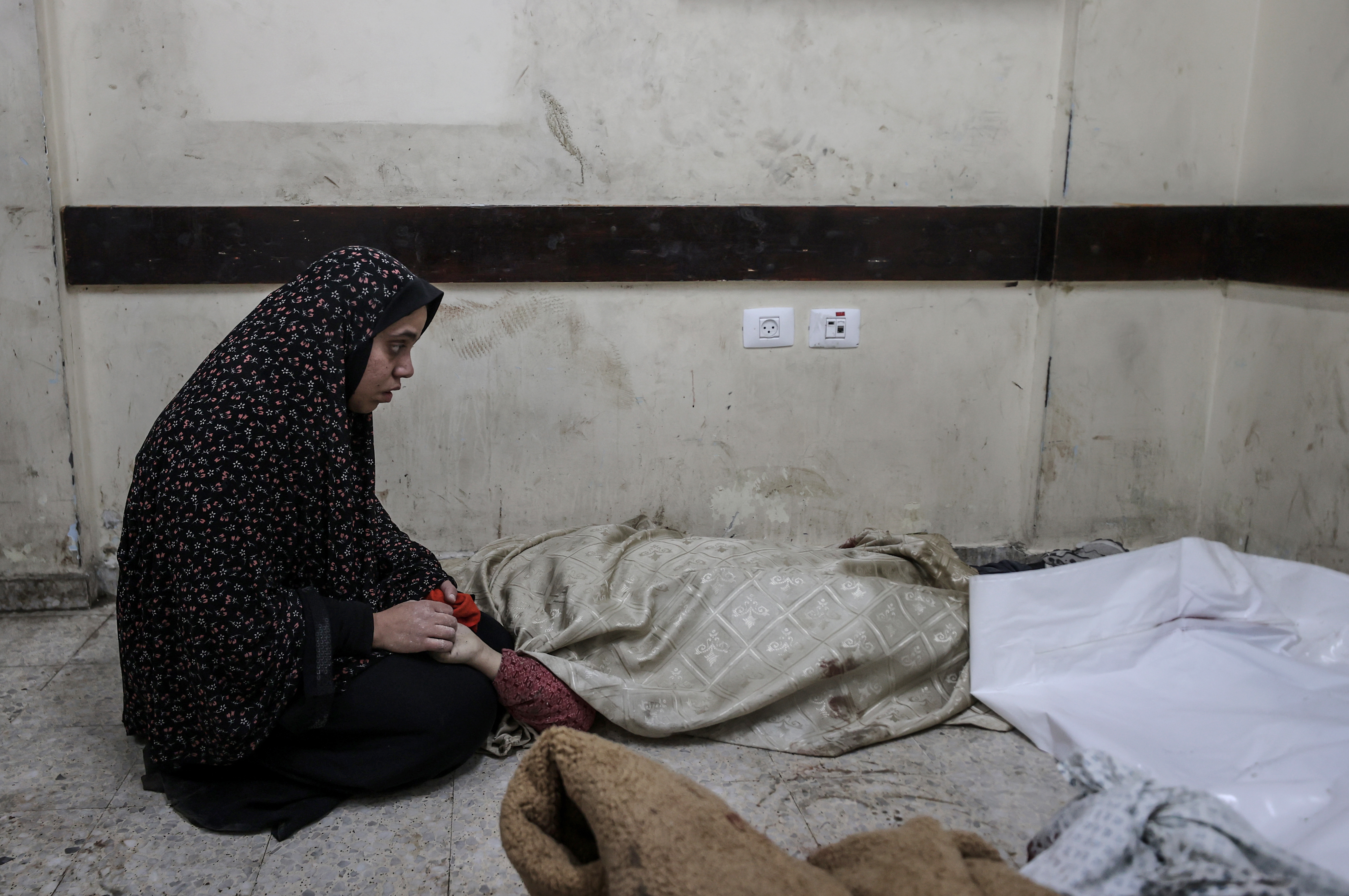 A Palestinian woman holds the hands of her child relative, whose body was brought to al-Awda Hospital after the Israeli army attacked the Nuseirat refugee camp in Gaza on December 29