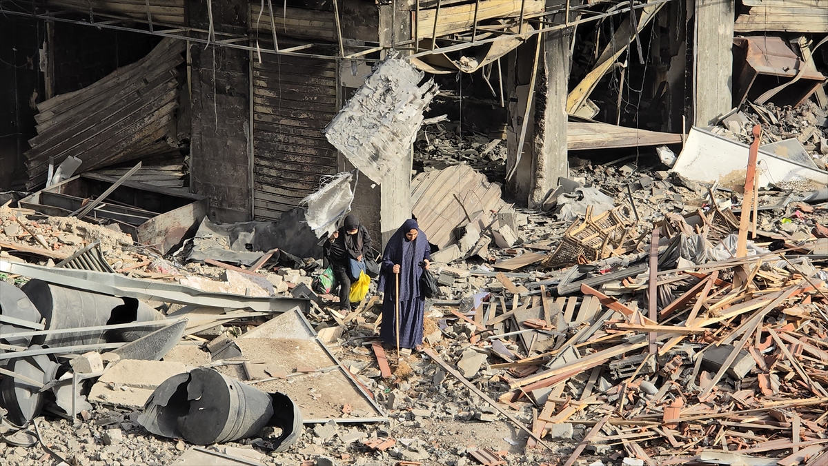 a woman walks with a stick through rubble