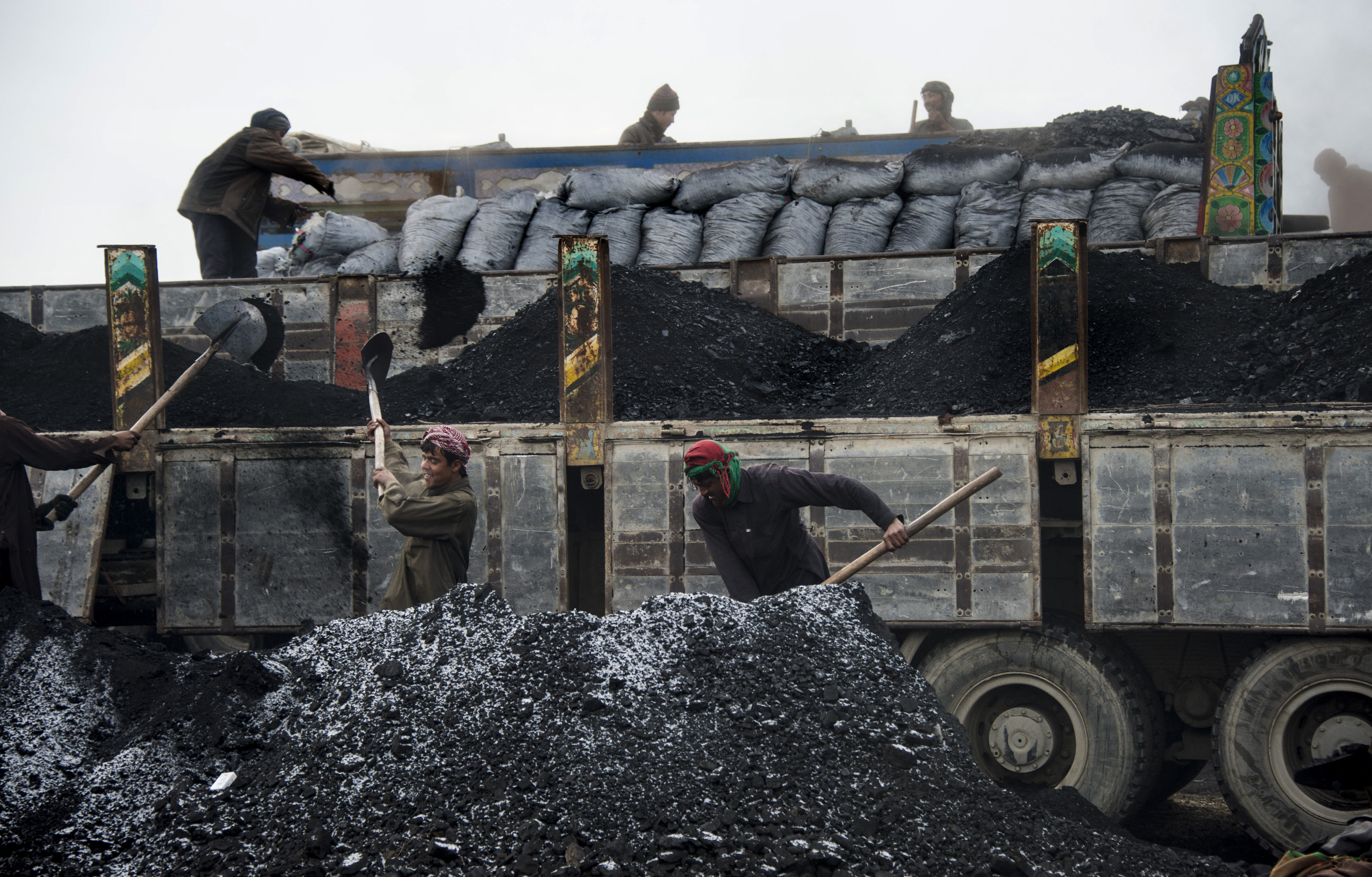 Afghan workers load coal onto a truck