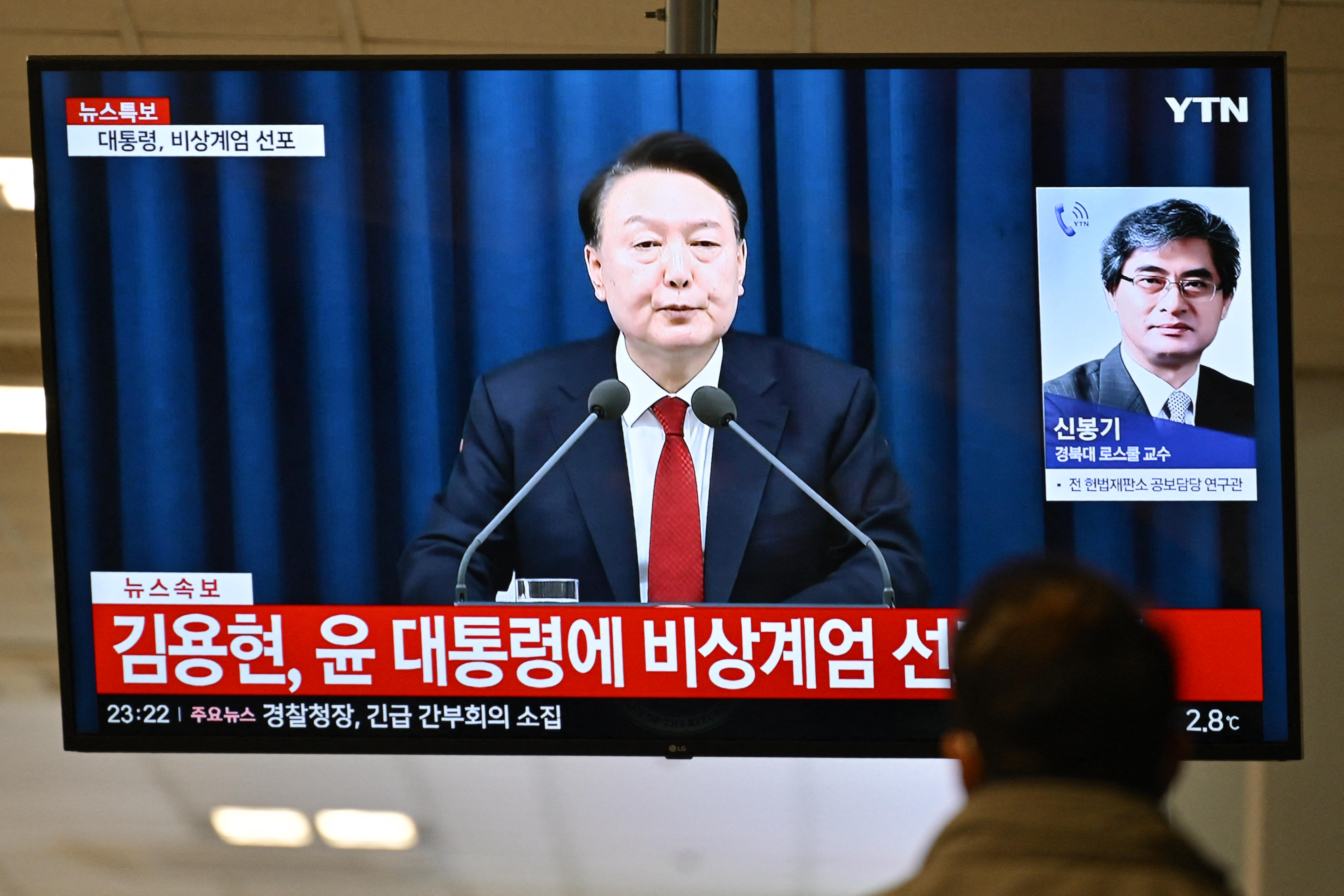A man watches South Korea's President Yoon Suk Yeol speak during a news broadcast on a television at a train station in Seoul on December 3, 2024