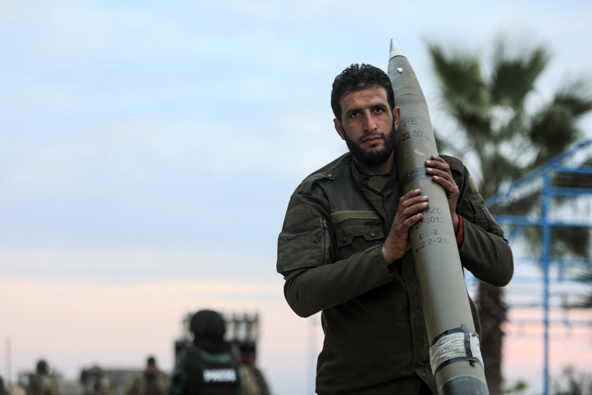 An anti-government fighter carries a rocket to be used against regime forces, in the northern outskirts of Syria's west-central city of Hama on December 4, 2024. - Syrian government forces pressed a counterattack against Islamist-led rebels around the key city of Hama on December 4 after suffering a string of staggering losses further north, a war monitor said. (Photo by Bakr AL KASSEM / AFP)