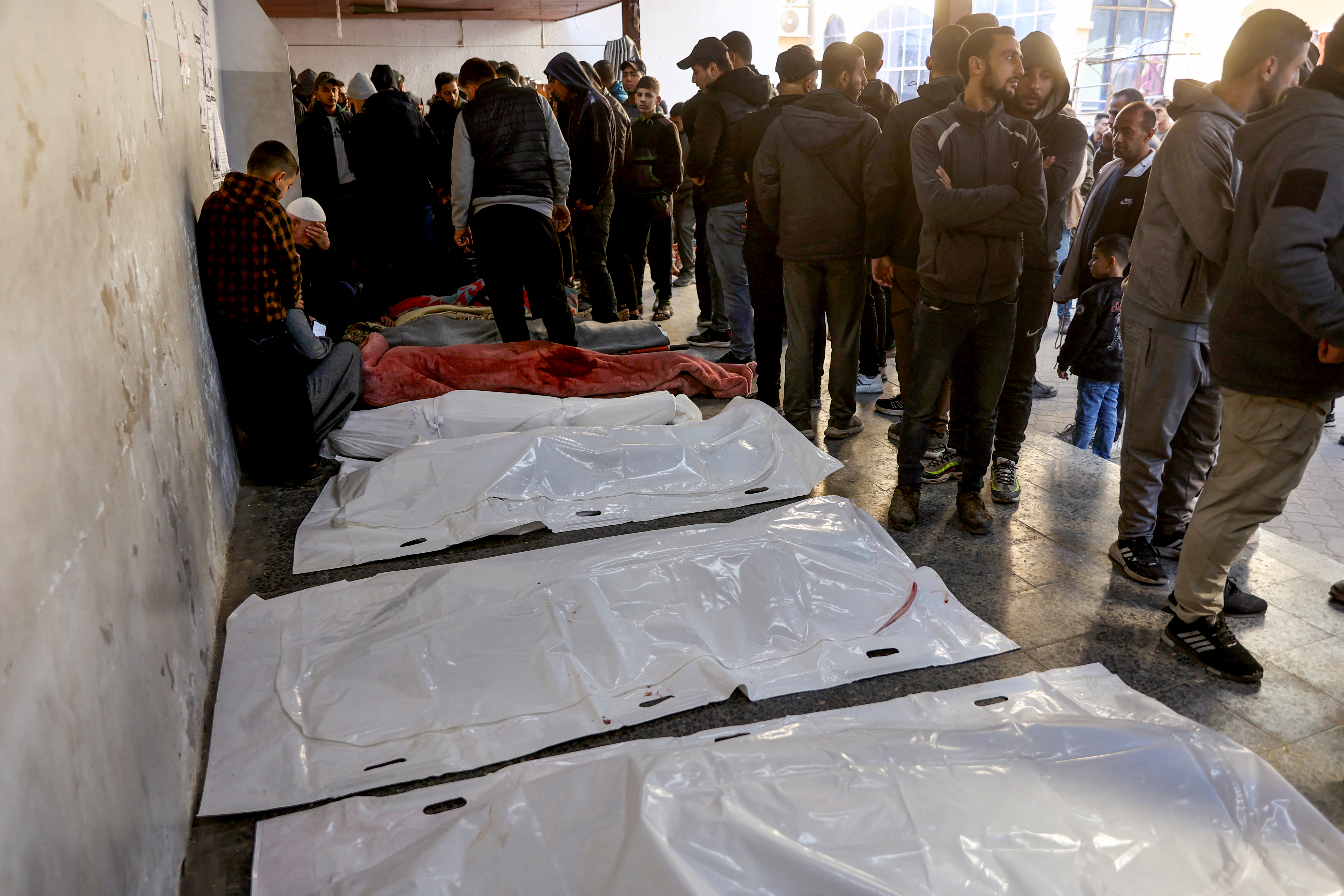 People mourn next to the bodies of loved ones killed during an Israeli strike, at Al-Ahli Arab hospital, also known as the Baptist hospital, in Gaza City on December 19