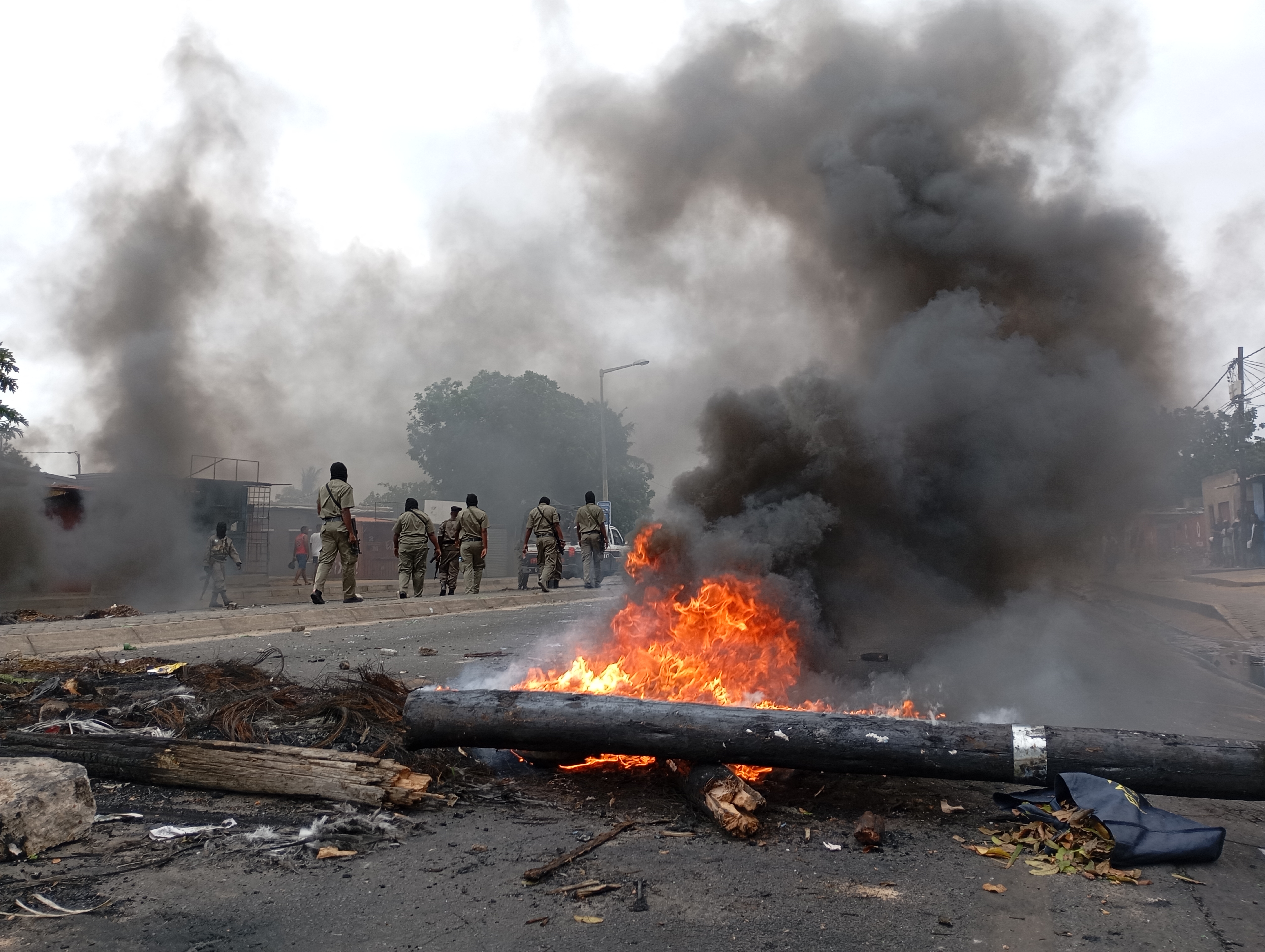 Pedestrians walk past a burning barricade in Maputo on December 24, 2024. - The capital of Mozambique was deserted on Tuesday, its main arteries heavily secured, noted AFP, the day after the confirmation of the victory in the October elections of Frelimo, in power for half a century, while the opposition maintains his denunciations of fraud. Maputo remains frozen in a climate of fear and insecurity on Christmas Eve after violent demonstrations in the evening and night. The police, in armored vehicles, patrol the center. (Photo by Amilton Neves / AFP)