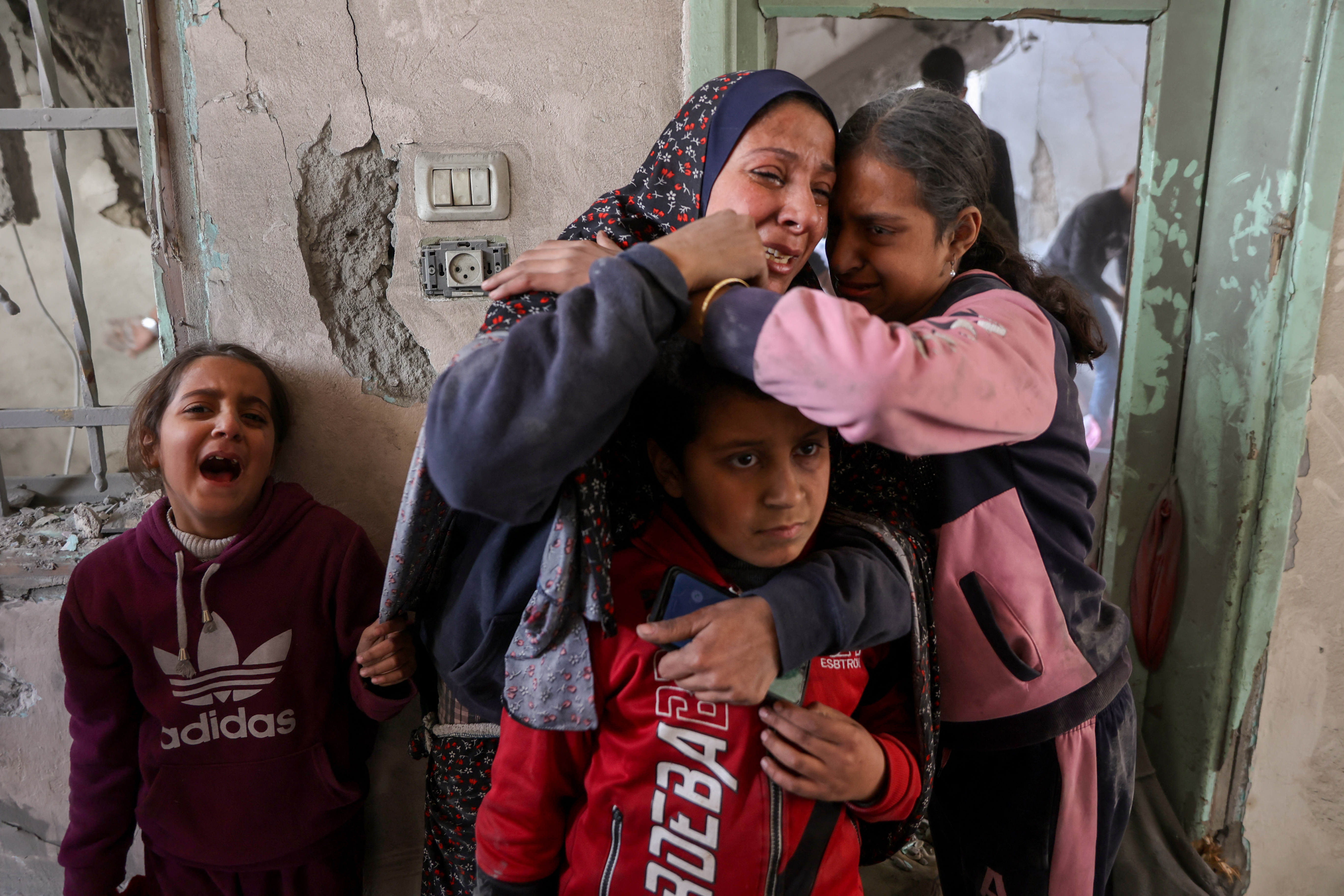 A woman and children react at the site of an Israeli strike in a residential area in the Tuffah neighbourhood, east of Gaza City, on December 26