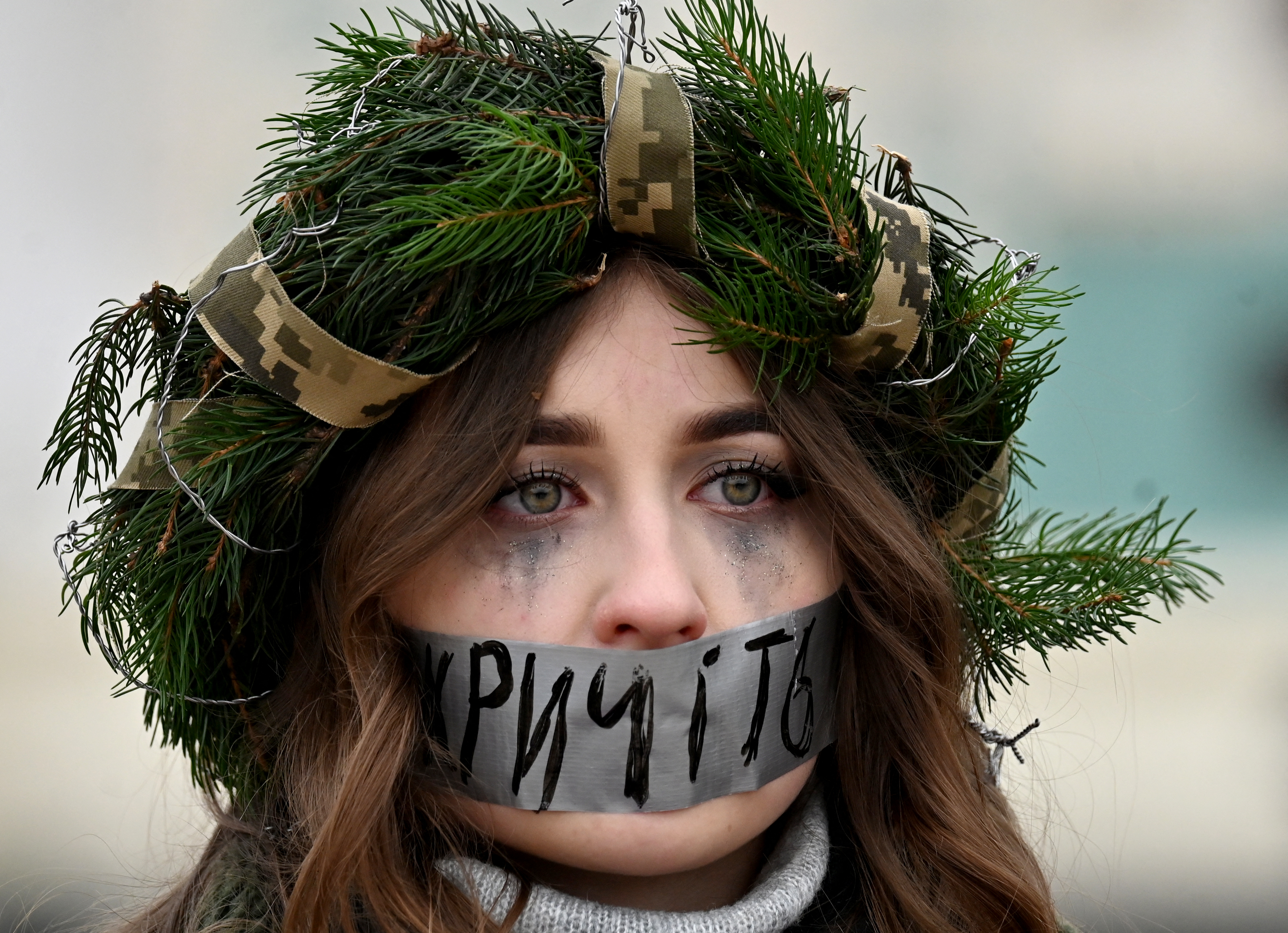 A protester wearing a Christmas wreath, has her mouth taped with a slogan which reads "Shout" during a rally to call for the exchangeas of Ukrainian prisoners of war from the Azov Brigade and other units with Russian prisoners at St. Sophia Square in Kyiv [File: Sergei Supinsky/AFP]