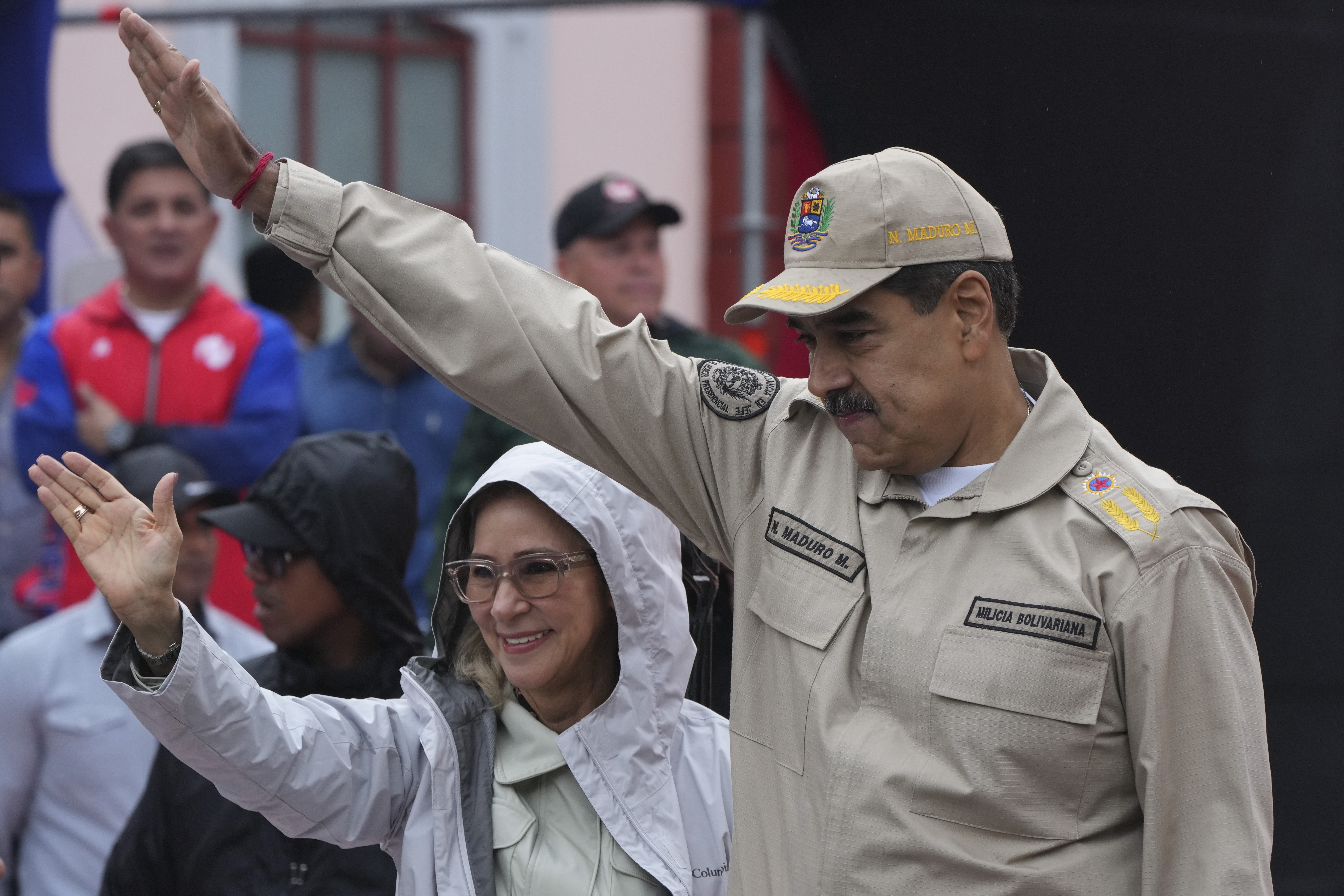 Nicolas Maduro and Cilia Flores lift an arm in salute at a public event