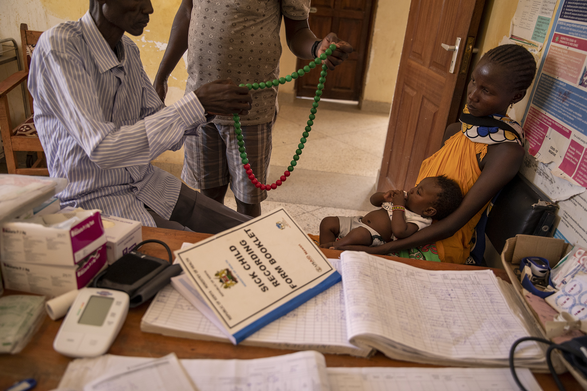 Doctors use a device to measure the heart rate of Quinta, 4 months old while her mother Nancy, 32 years old holds her inside the examination room of the Kangatosa Health Centre located in Turkana County, northwest Kenya on October 19, 2024. Kangatosa Health Centre welcomes women and children from the surrounding villages to provide them with medicines, food supplements and to monitor their health conditions, which are put at risk by the severe drought that is affecting the country. [Alessio Paduano/Al Jazeera]