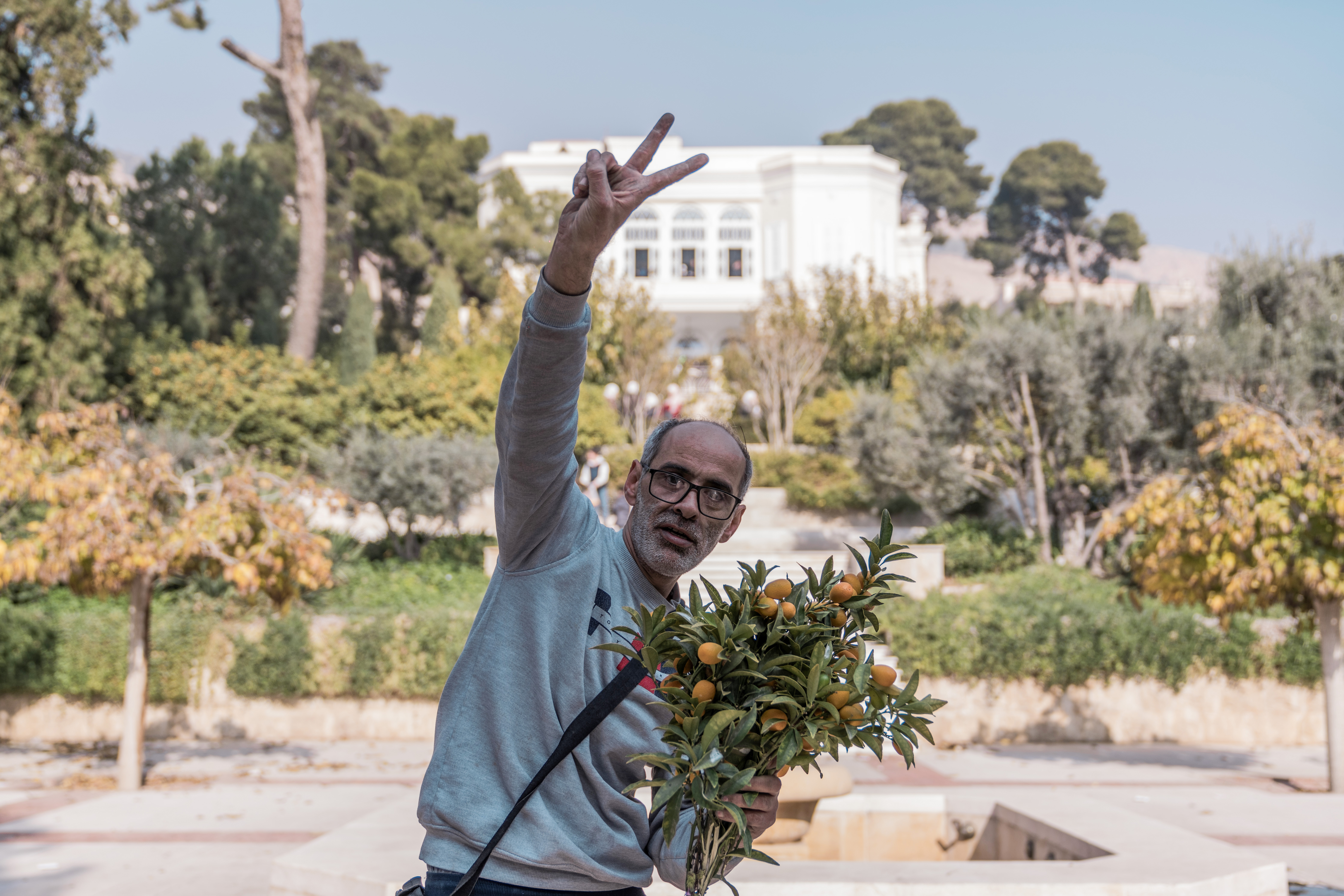 A man poses holding kumqauts in front of a villa formerly belonging to Bashar al-Assad