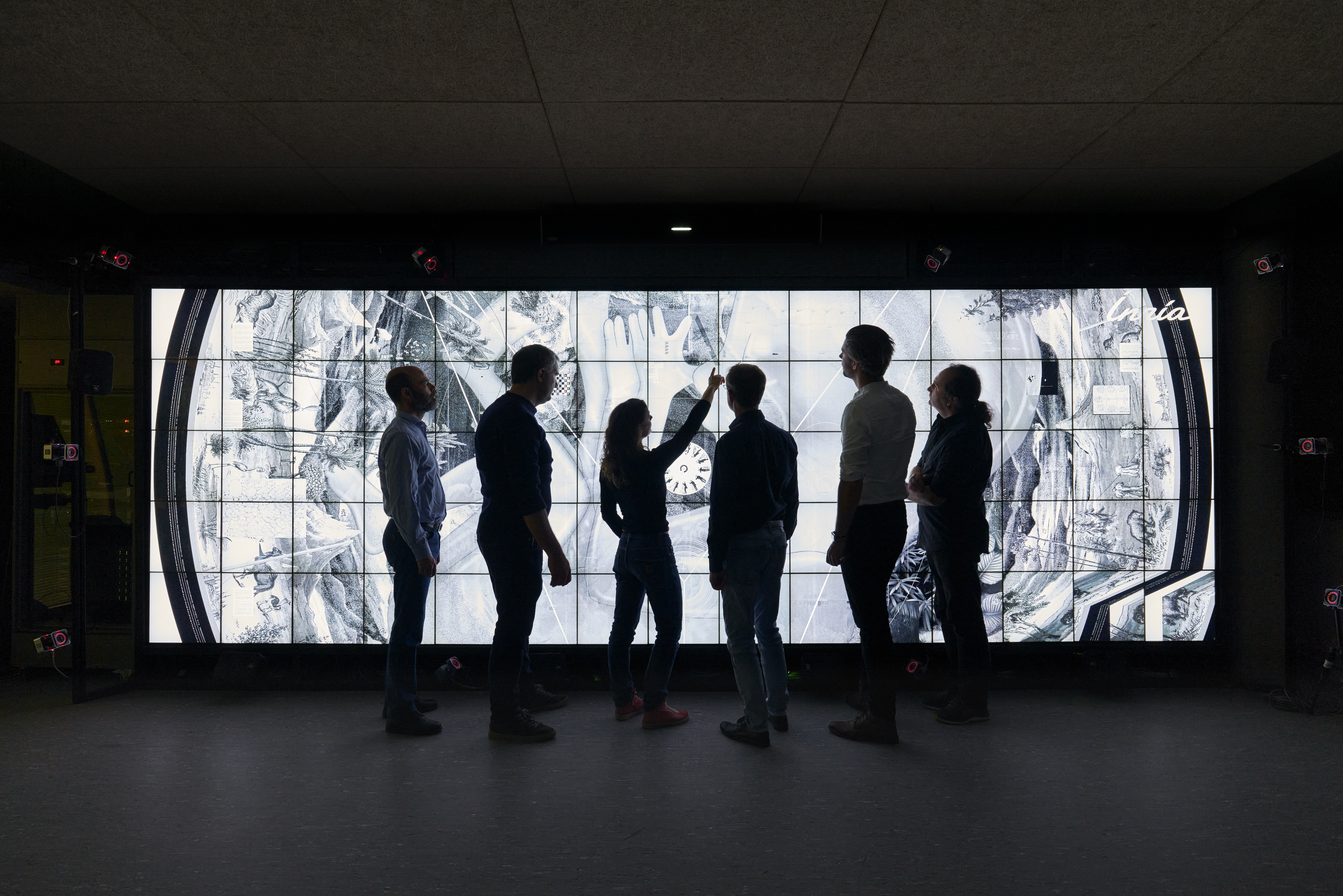 Members of the Sanctuary team look at some of the designs of the Life disc on the images wall, at Inria Saclay, Paris [Courtesy of Benedict Redgrove]