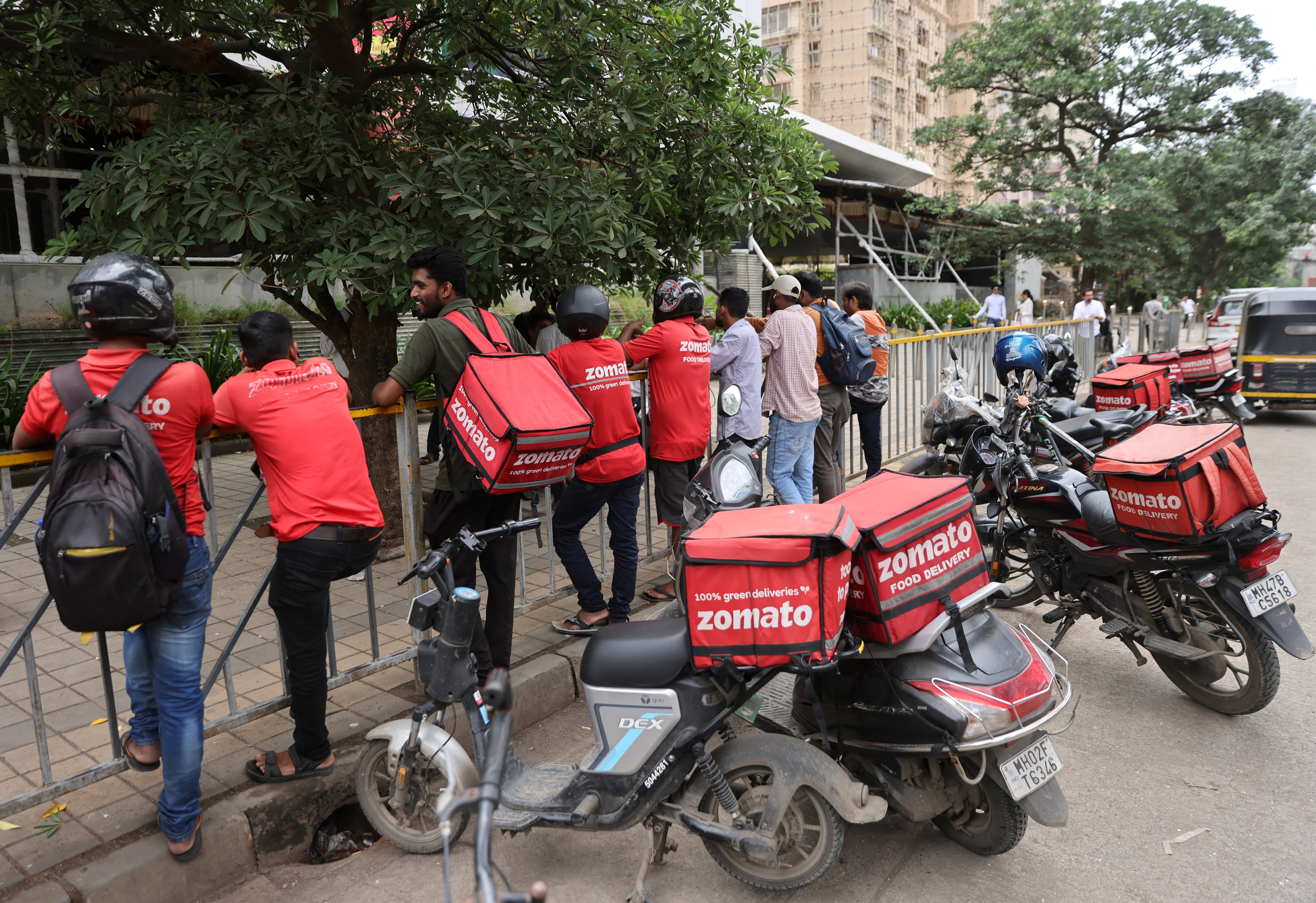 Gig workers wait in line to collect their delivery order outside a mall in Mumbai, India