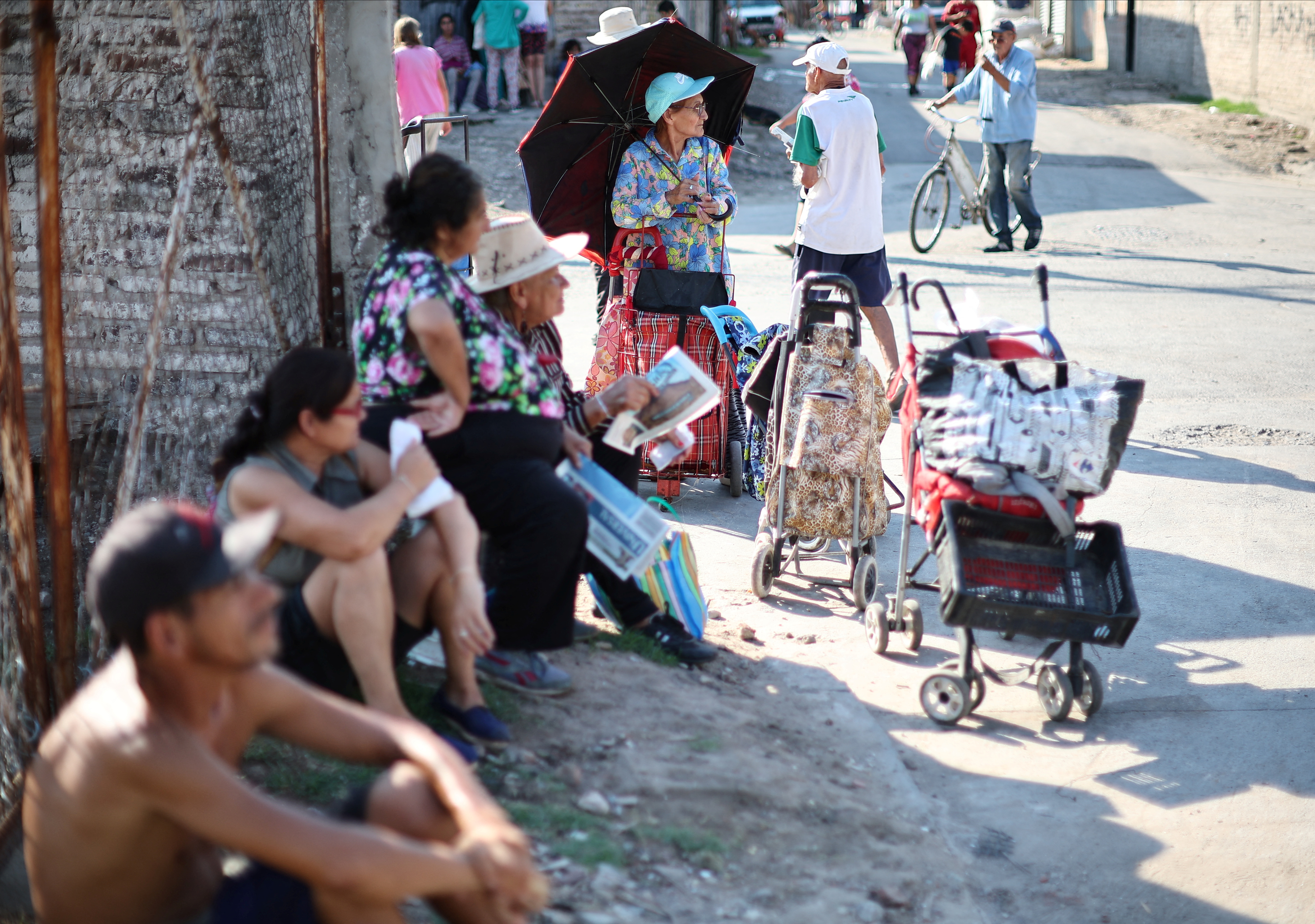 People sit in the shade next to a wall in Villa Fiorito