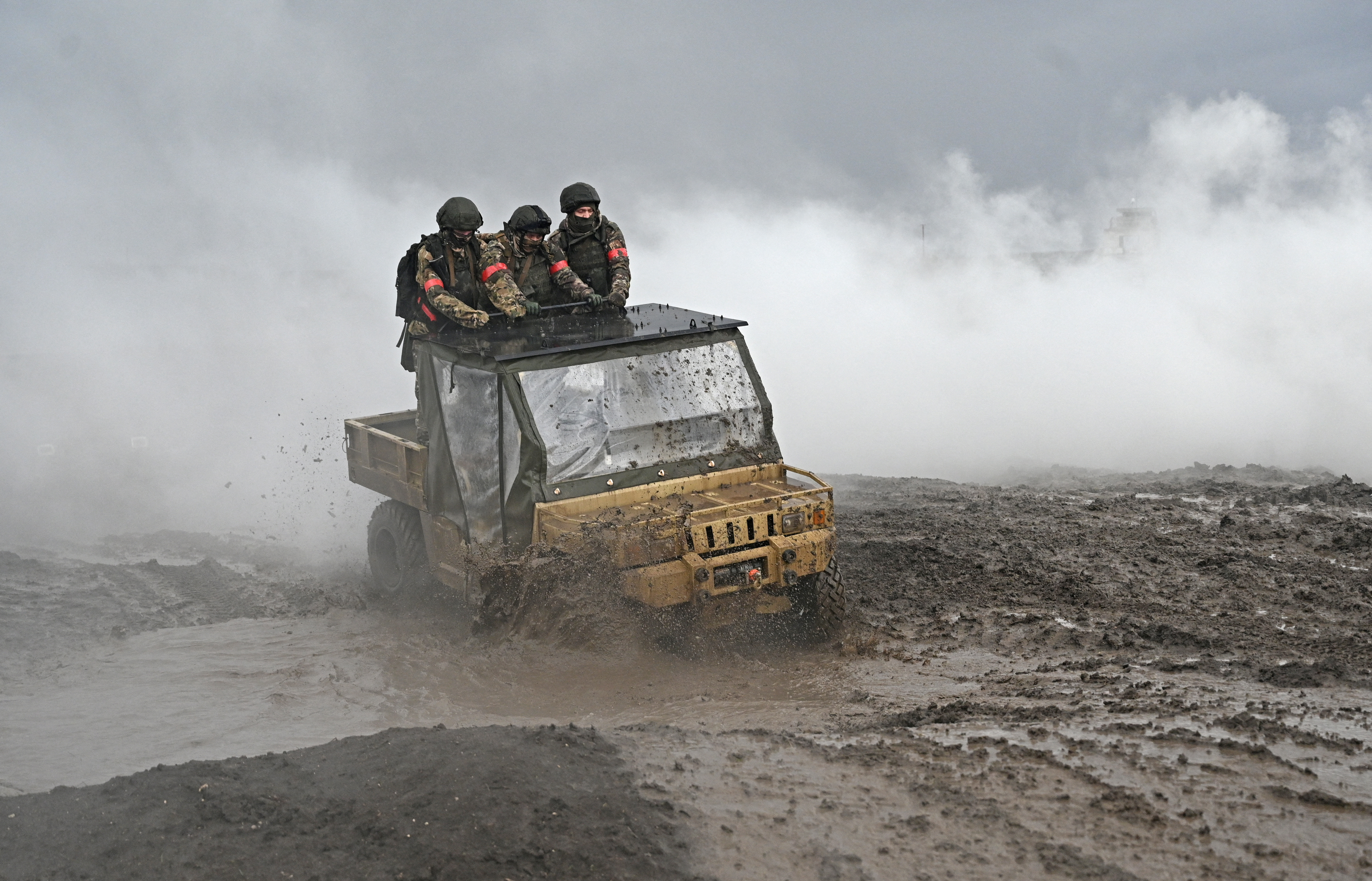 Russian service members ride a military buggy during combat training at a firing range