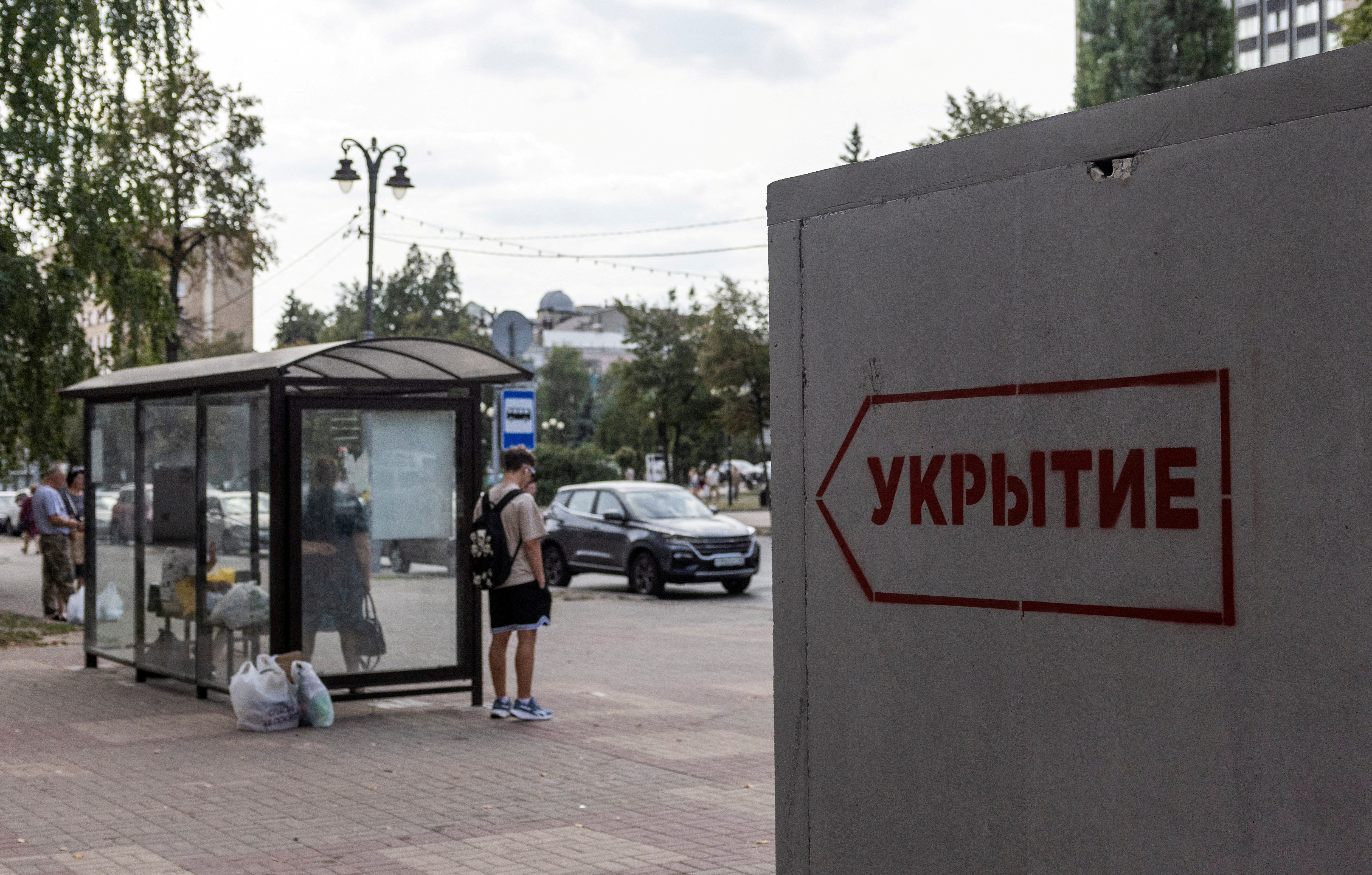 FILE PHOTO: People wait at a bus stop next to a reinforced concrete bomb shelter installed in a street in the course of Russia-Ukraine conflict, in Kursk, Russia August 28, 2024. The sign on the construction reads: "Shelter". REUTERS/Maxim Shemetov/File Photo