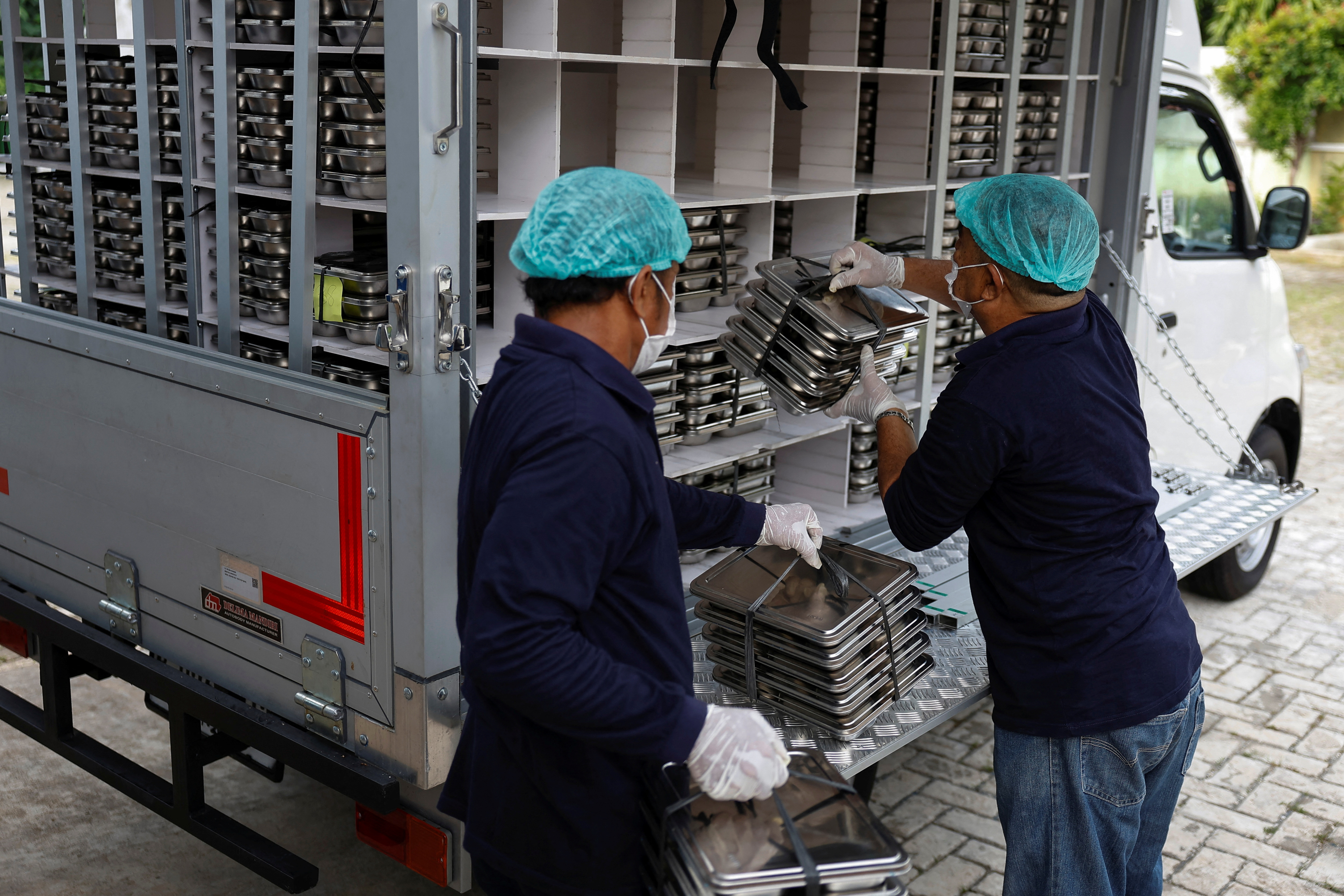 Staff members load meal boxes onto a truck to be distributed for free to children and pregnant women, at a kitchen in Jakarta, Indonesia
