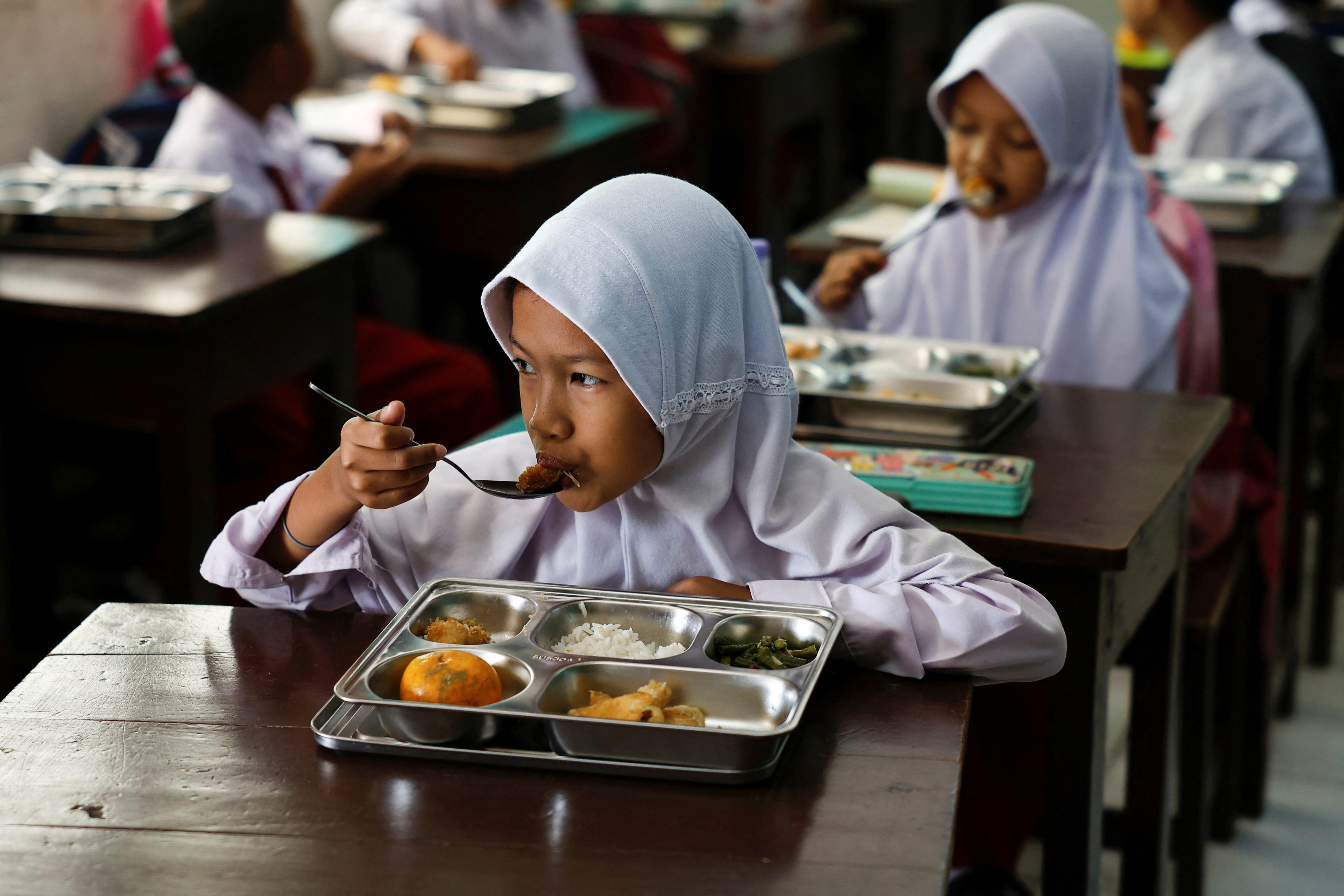 Students eat meals from the free nutritious meals program at a school in Jakarta, Indonesia, January 6