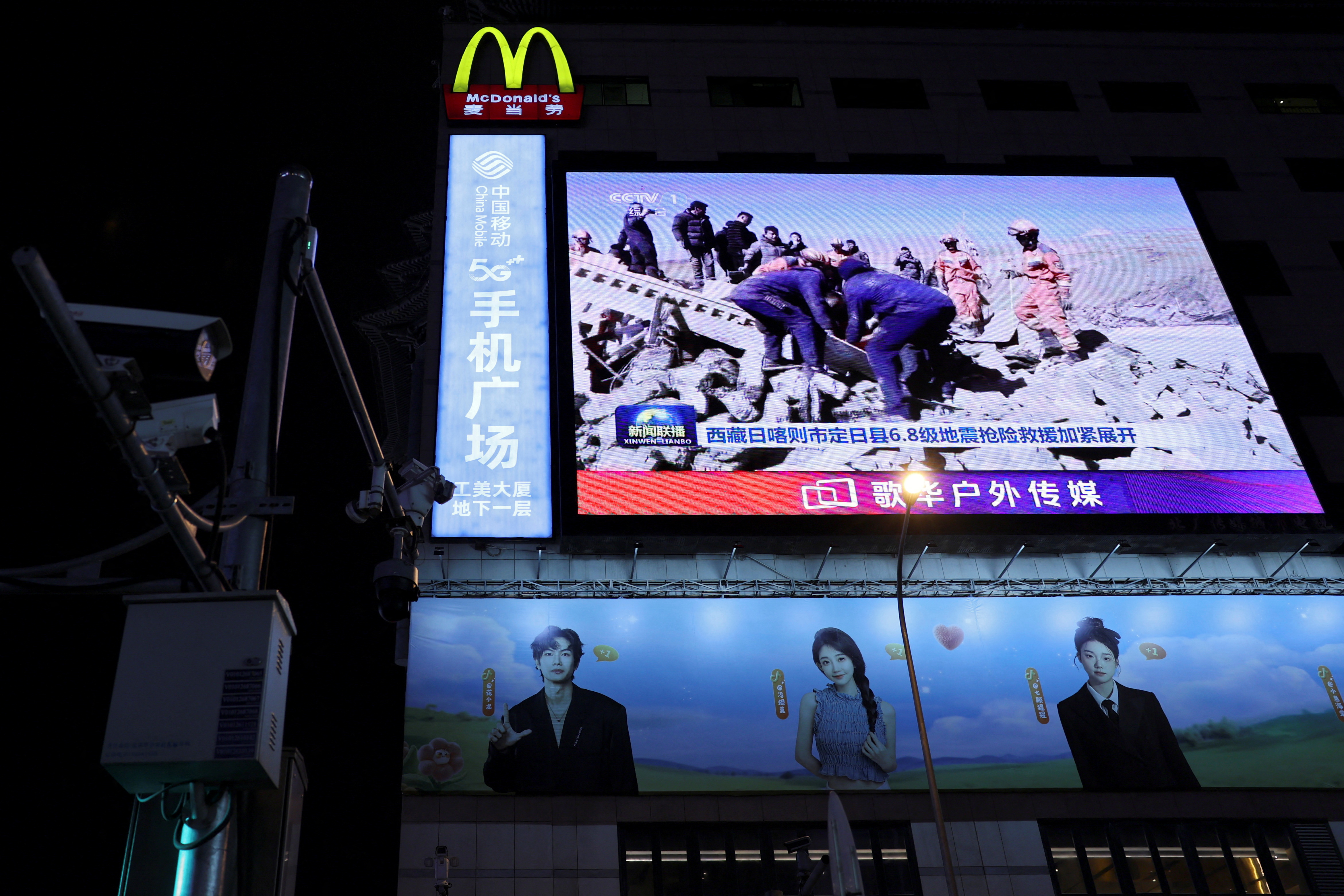 A giant screen shows news footage of rescue workers at a search and rescue operation after an earthquake struck Tingri county, Shigatse, in Tibet region, at a shopping street in Beijing, China January 7