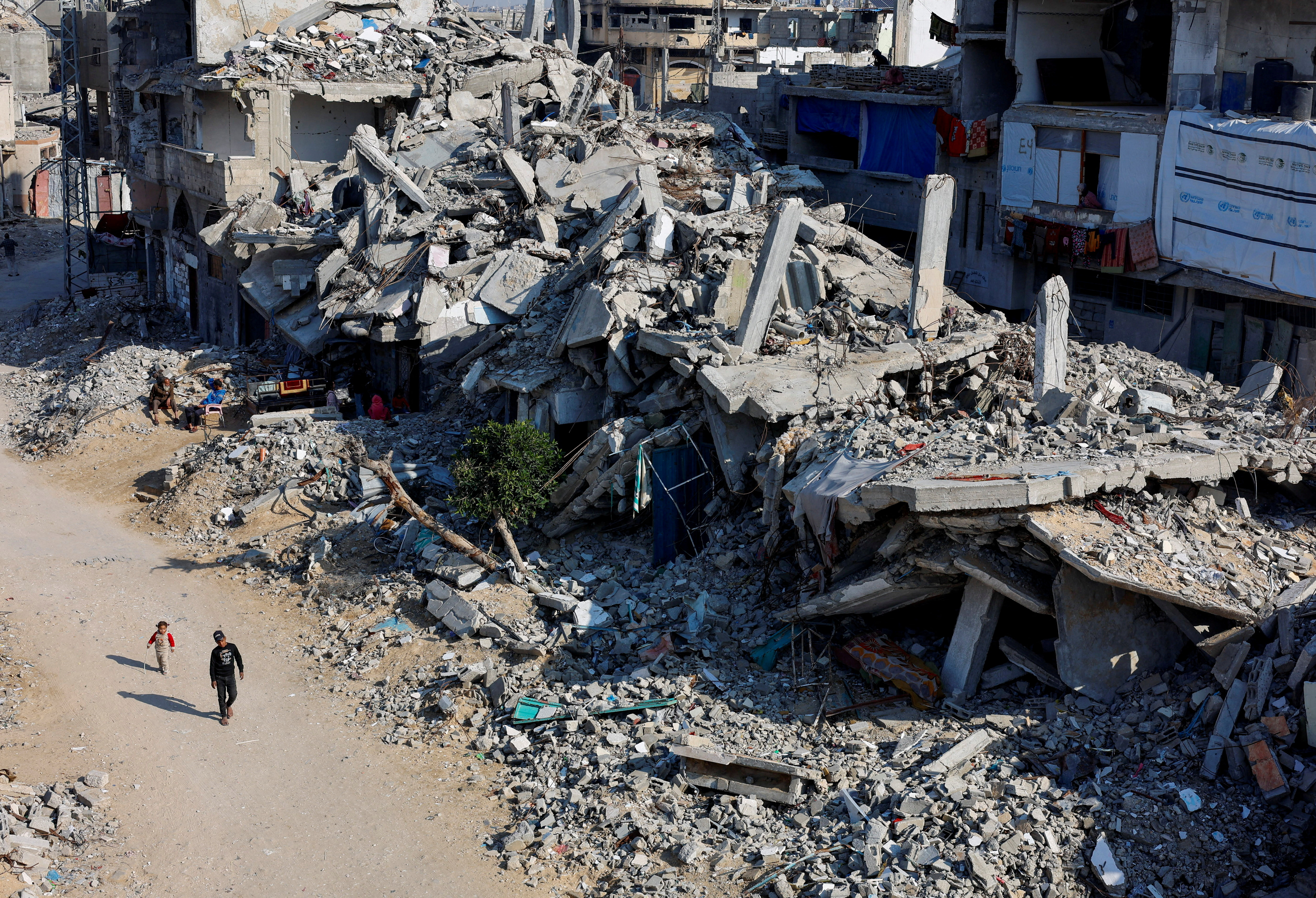 FILE PHOTO: Palestinian children walk past the rubble of houses, destroyed in previous Israeli strikes, amid the Israel-Hamas conflict, in Khan Younis, southern Gaza Strip, January 7, 2025. REUTERS/Mohammed Salem/File Photo