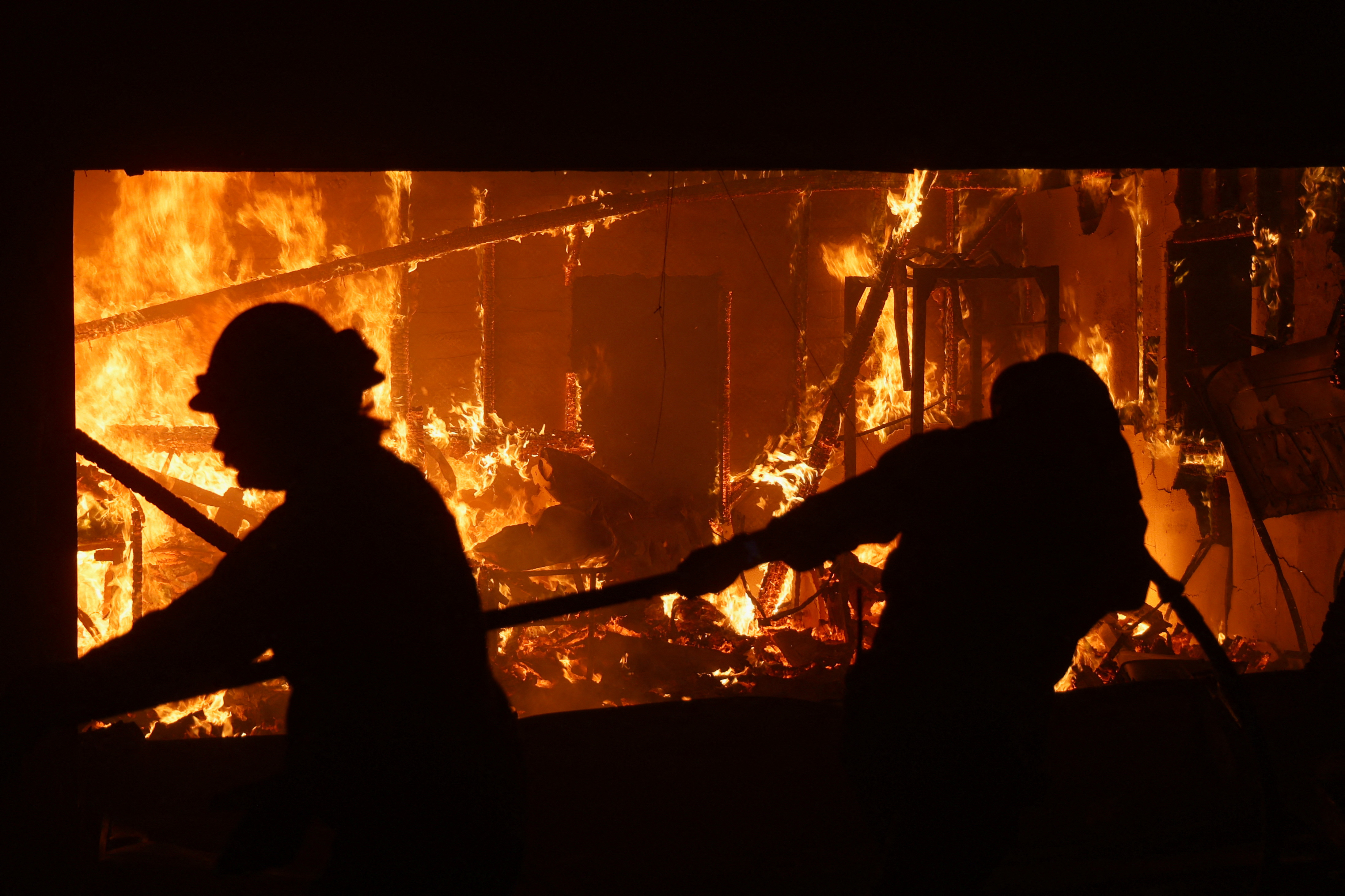Firefighters work to extinguish flames as the Eaton Fire burns in Pasadena, California