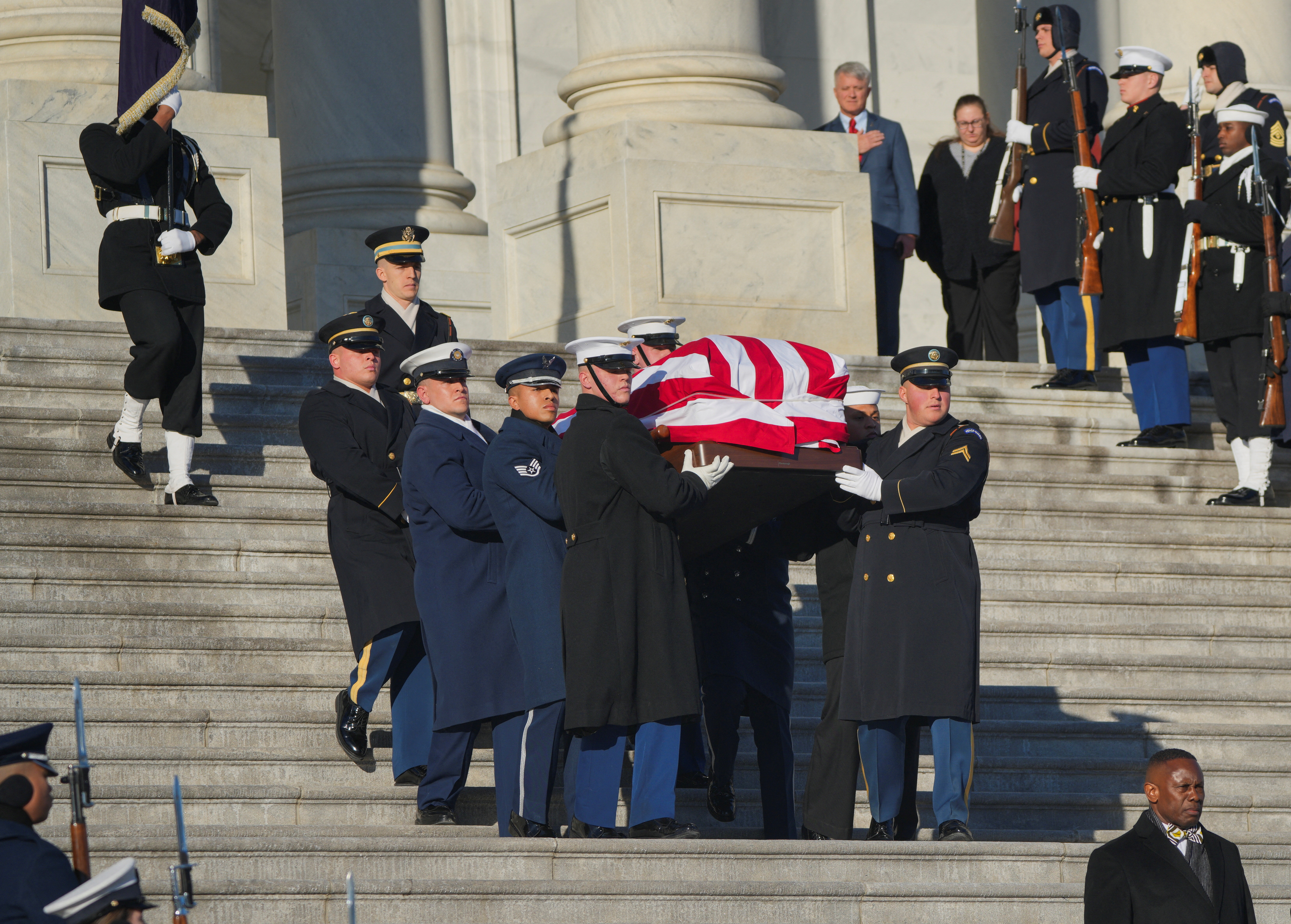 Military honour guard carry the casket of former US President Jimmy Carter down steps at the US Capitol