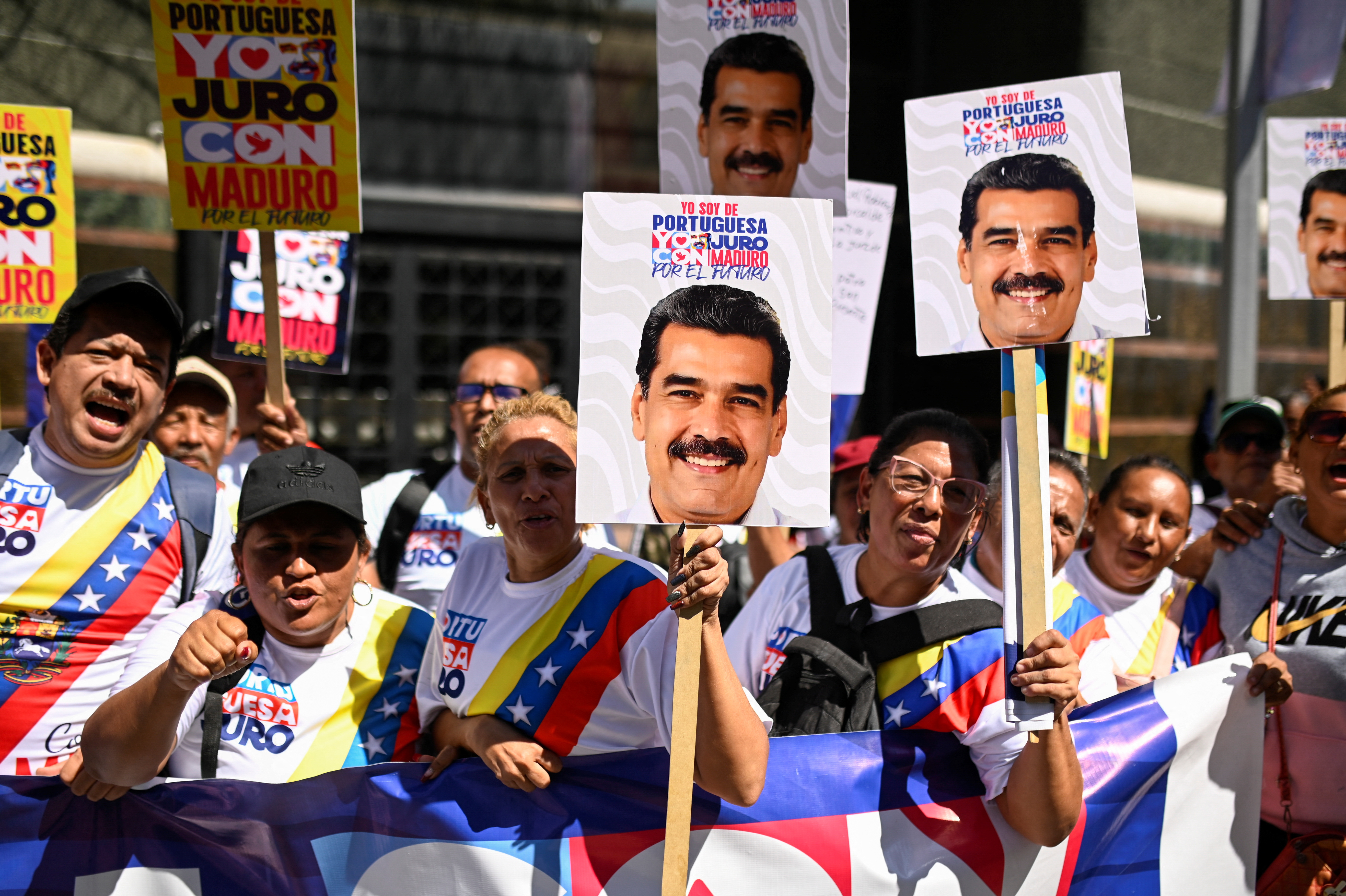 Supporters of Nicolas Maduro wave picket signs with his face.