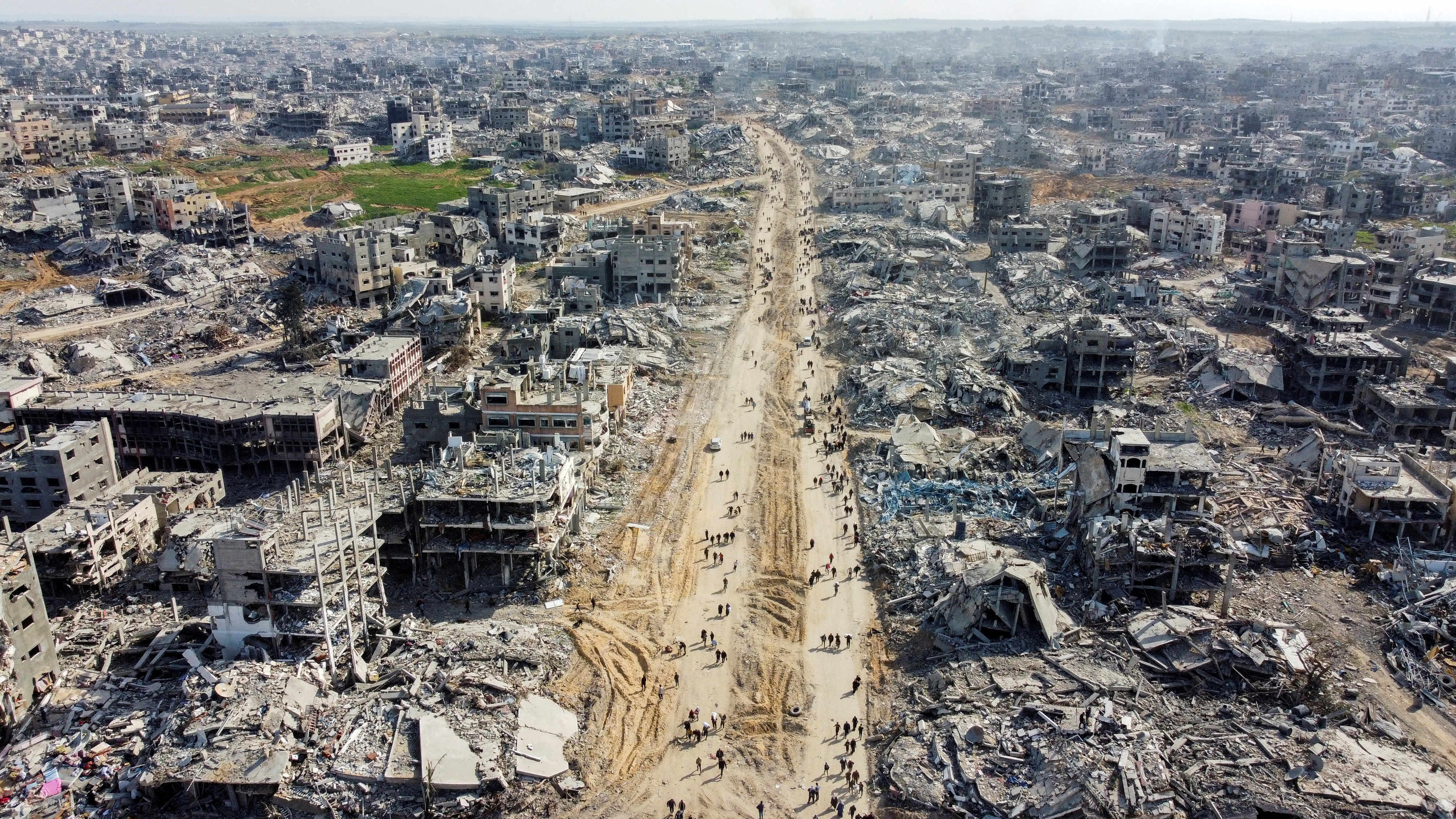 A drone view shows Palestinians walking past the rubble of houses and buildings in Jabalia in the northern Gaza Strip