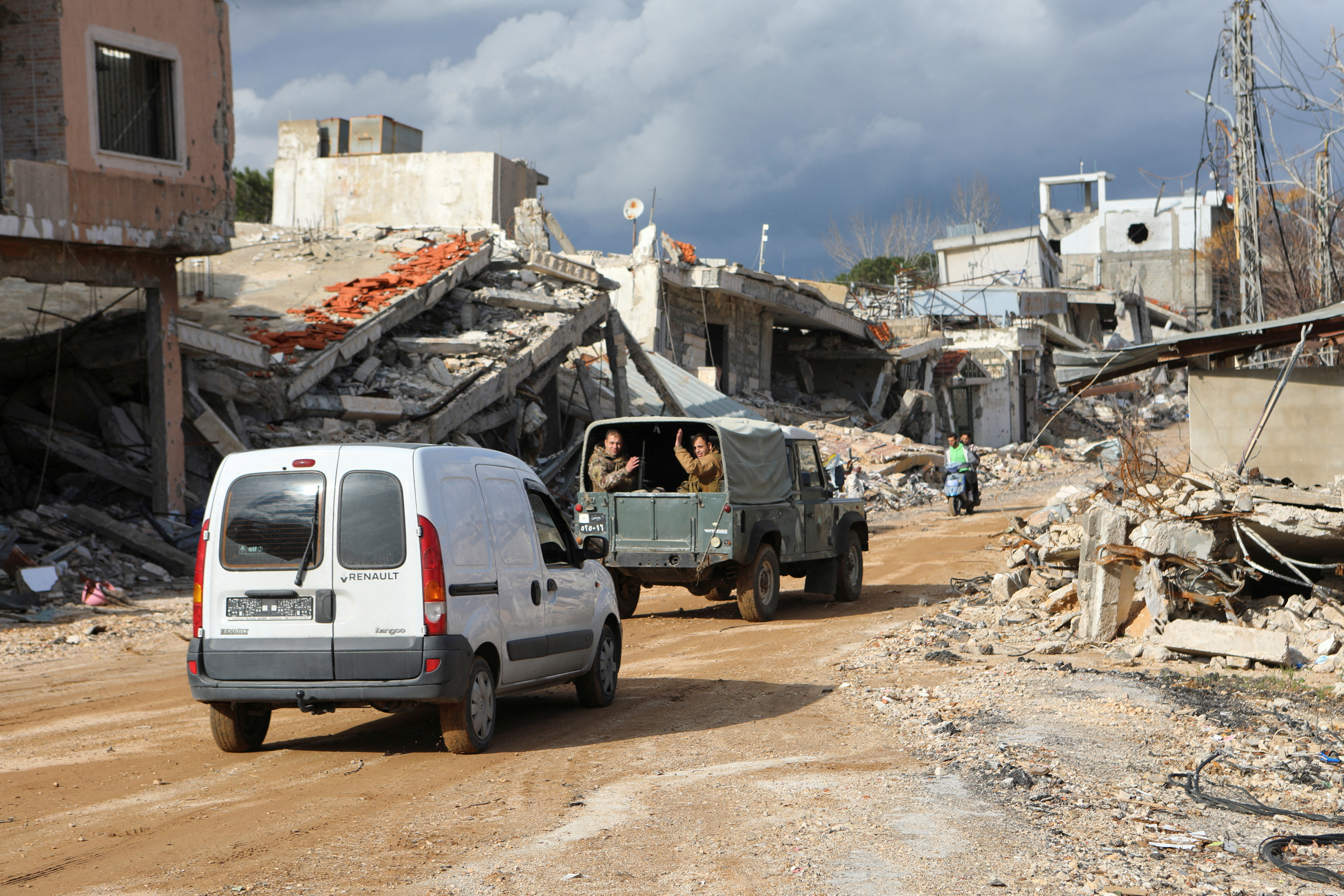 Lebanese army members gesture as they drive through a damaged site at the Lebanese village of Khiam, near the border with Israel