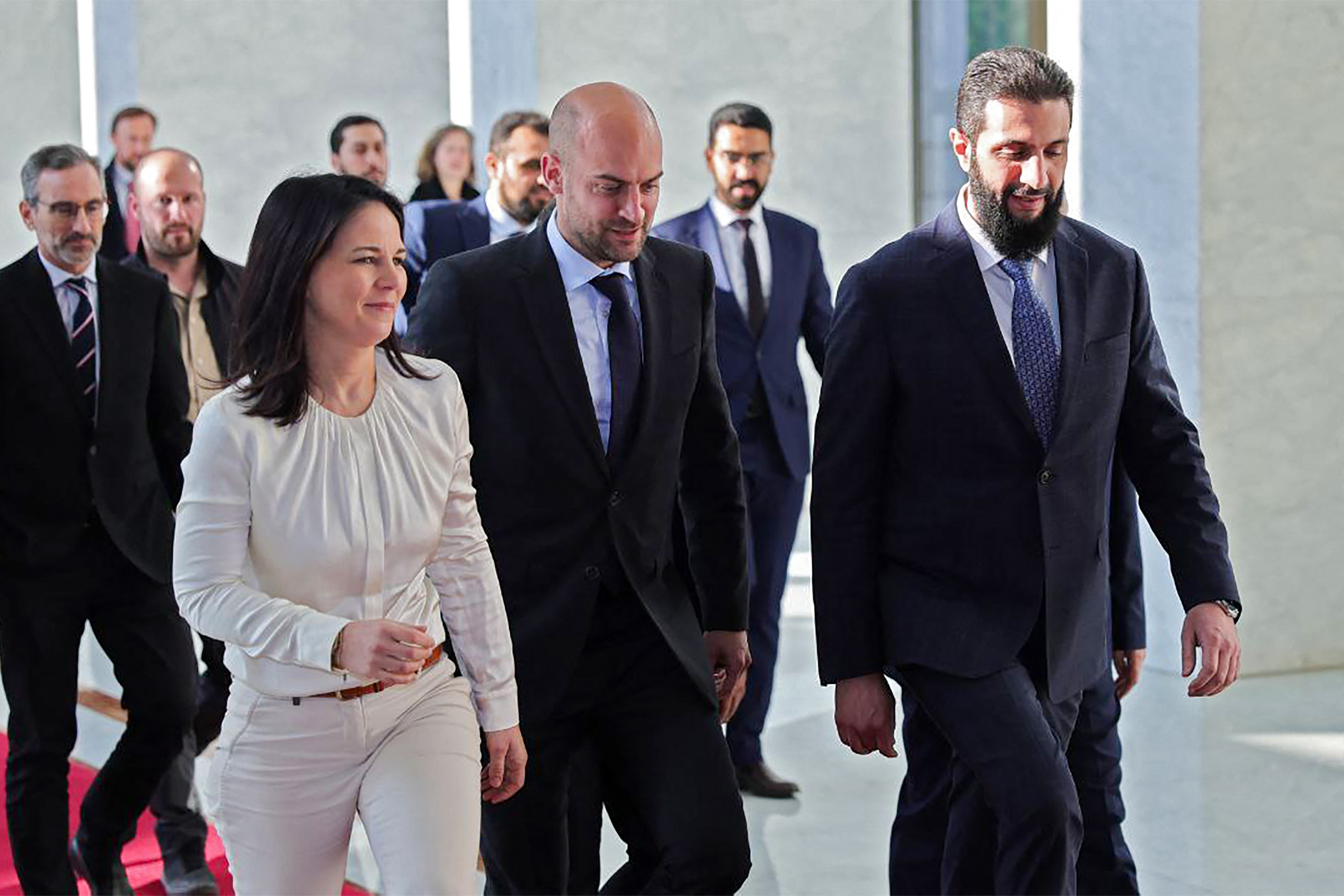 France's Foreign Minister Jean-Noel Barrot (C) and Germany's Foreign Minister Annalena Baerbock (L) walking with Syria's new ruler Ahmed al-Sharaa