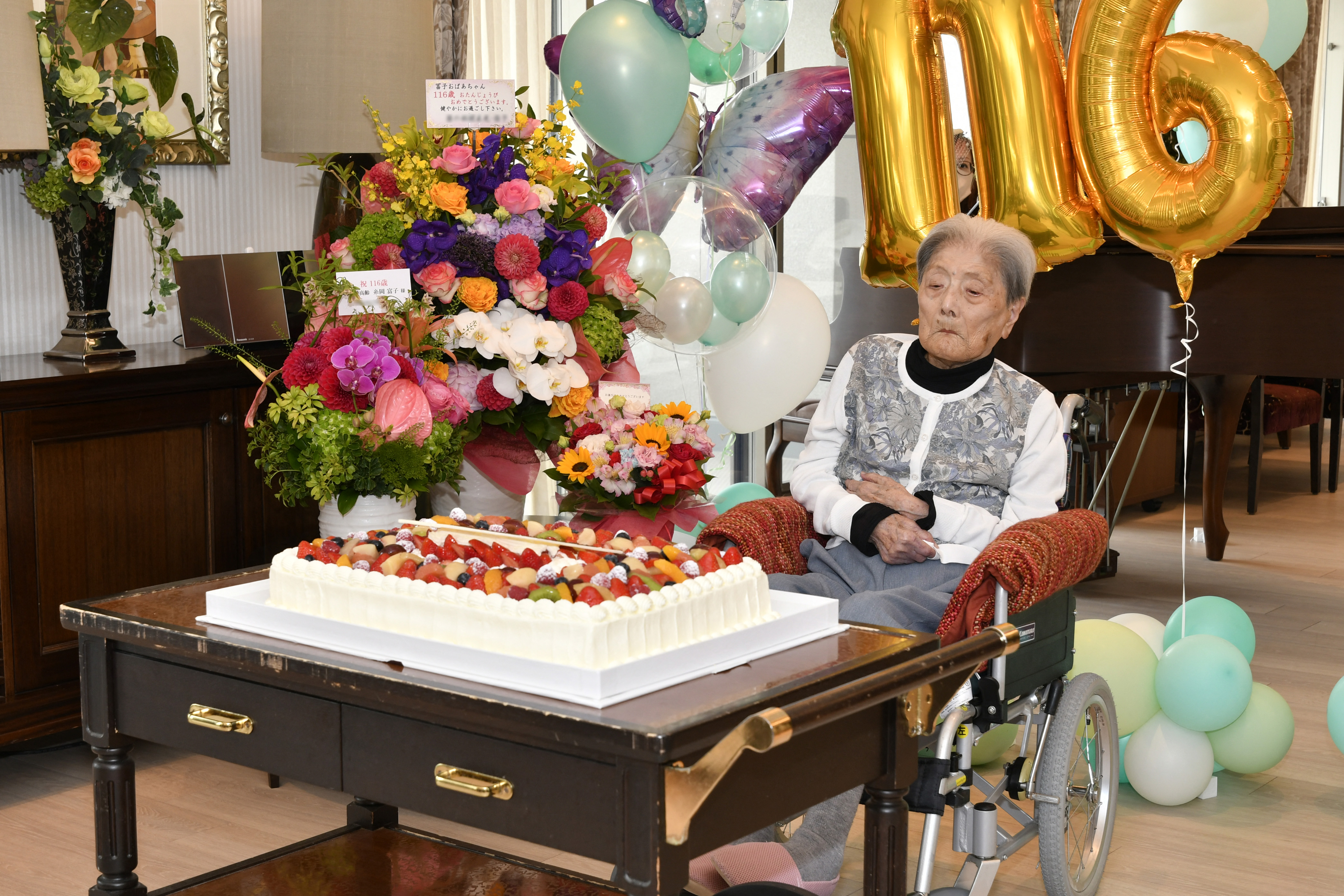 Tomiko Itooka celebrates her 116th birthday with a cake and flowers in front of her.