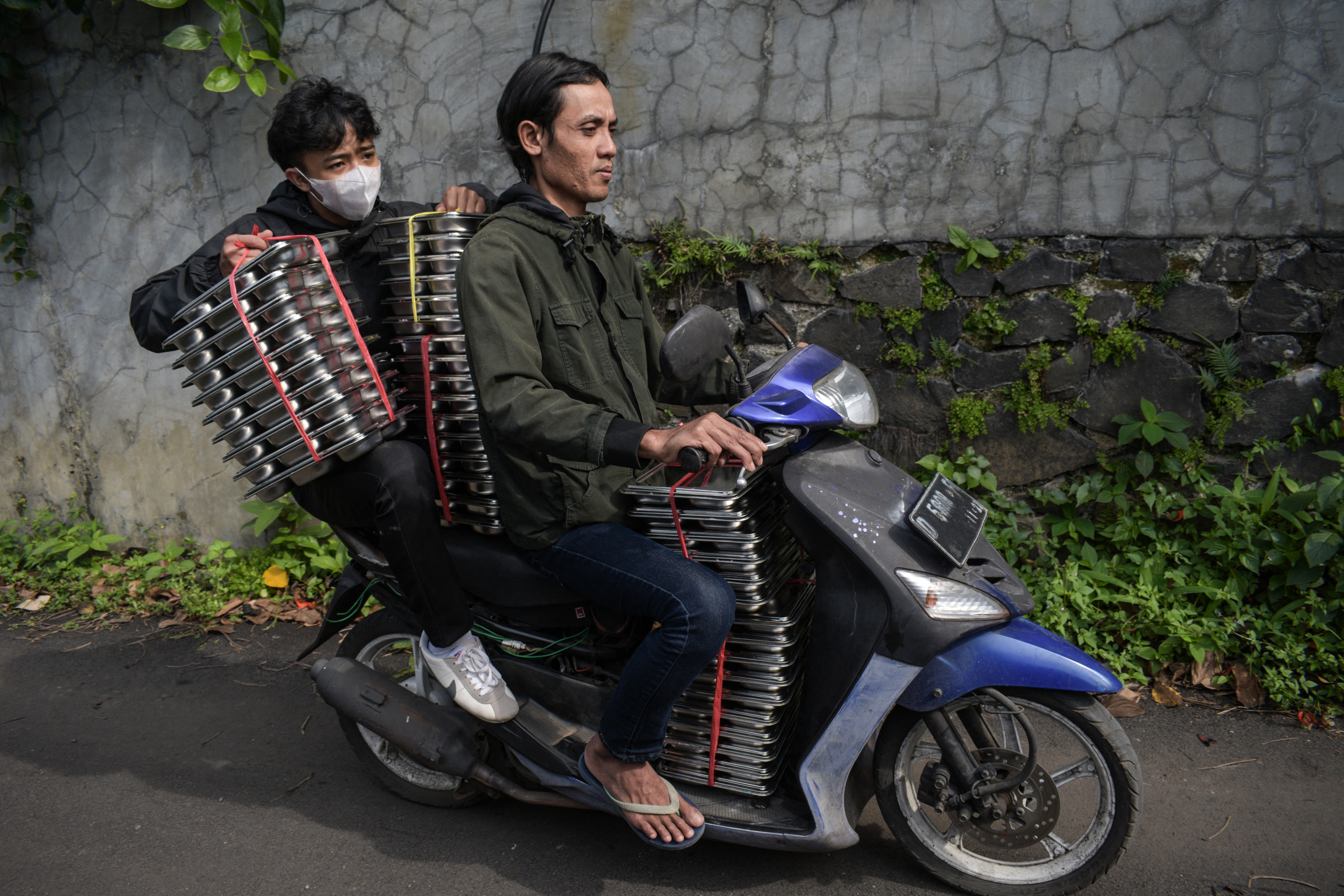 Workers deliver lunch plates to schools by a scoooter in Cimahi, West Java, on January 6
