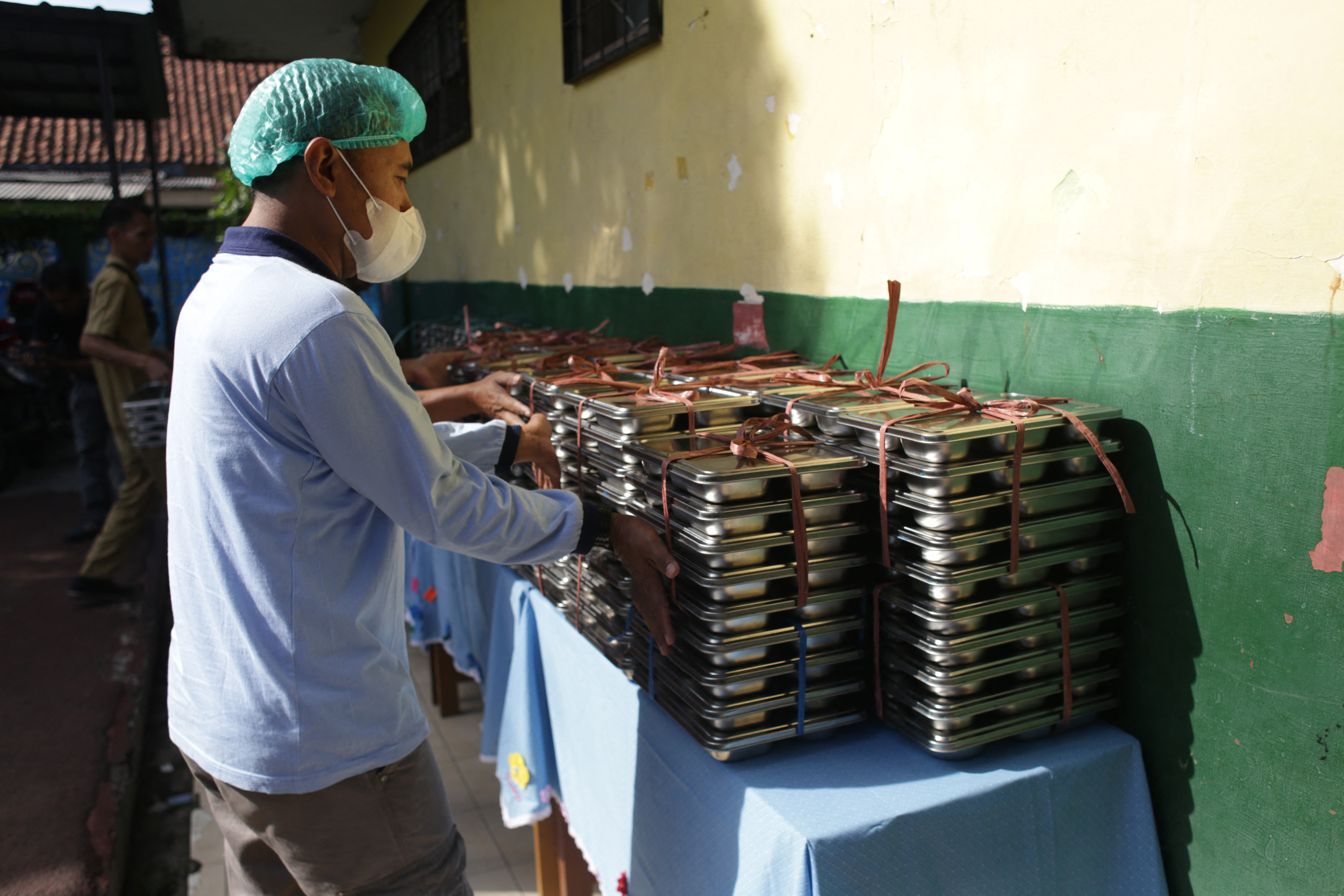 A staff member prepares lunch plates to deliver on the first day of a free-meal program at a public kitchen in Bogor, West Java, Indonesia, on January 6