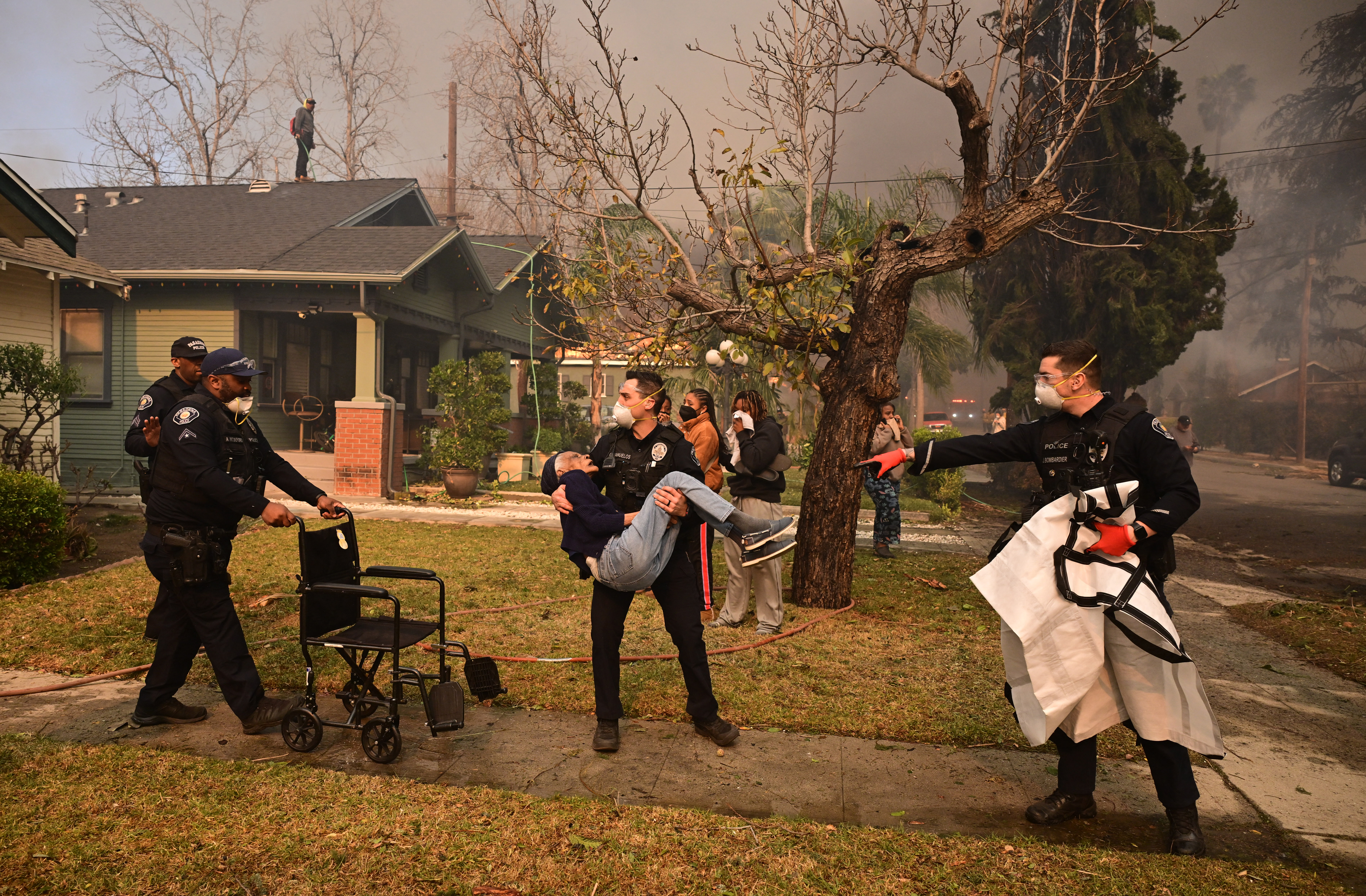 Police officers remove an elderly resident from her home during the Eaton Fire in Altadena, California, on January 8